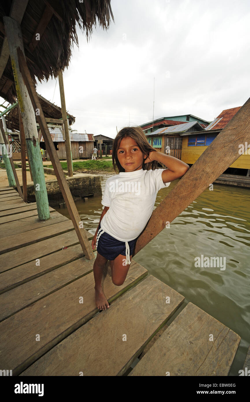 girl leaning at a support log of a projecting roof over a landing stage, Honduras, Brus Laguna Stock Photo