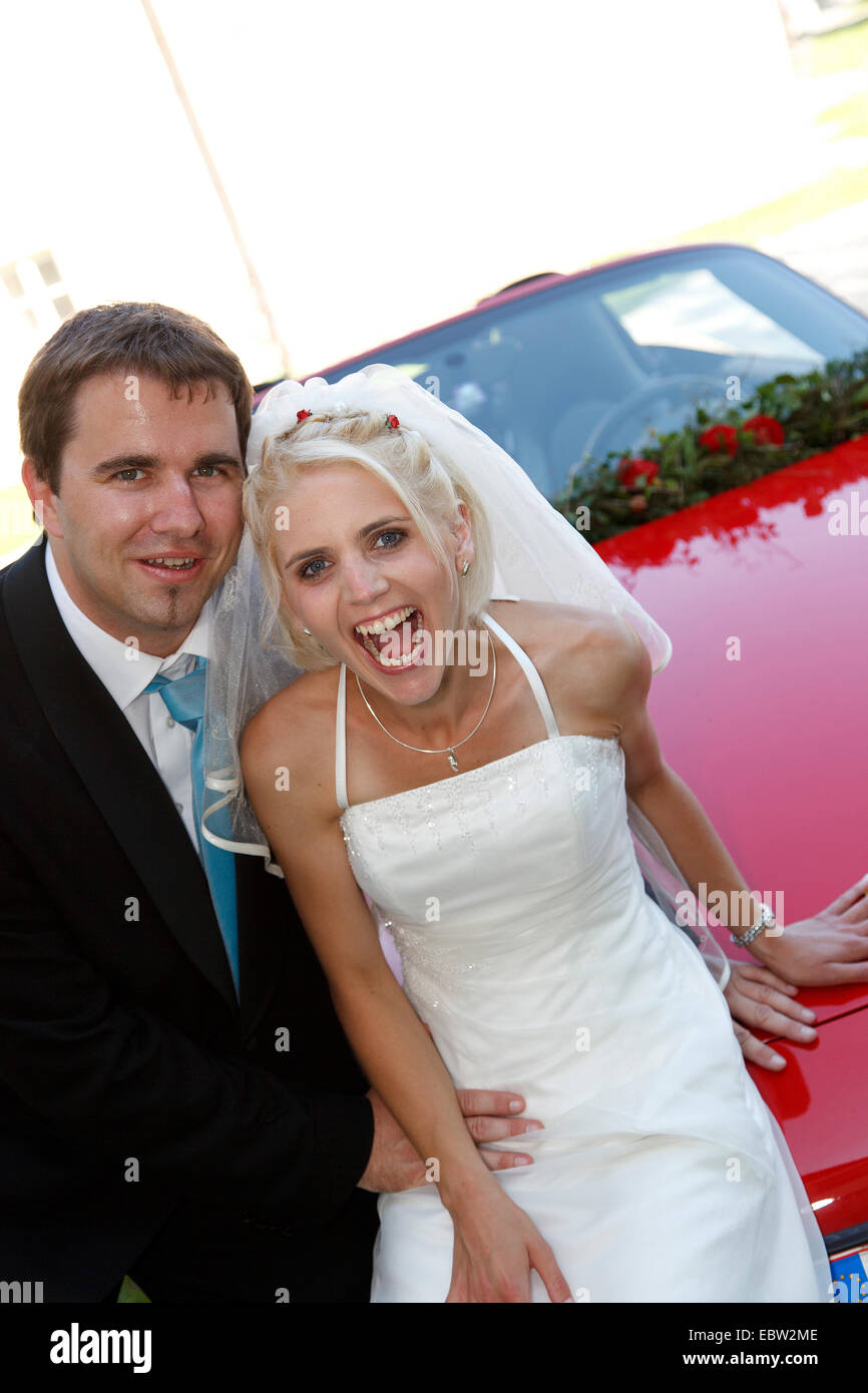 bridal couple posing on red sports car Stock Photo