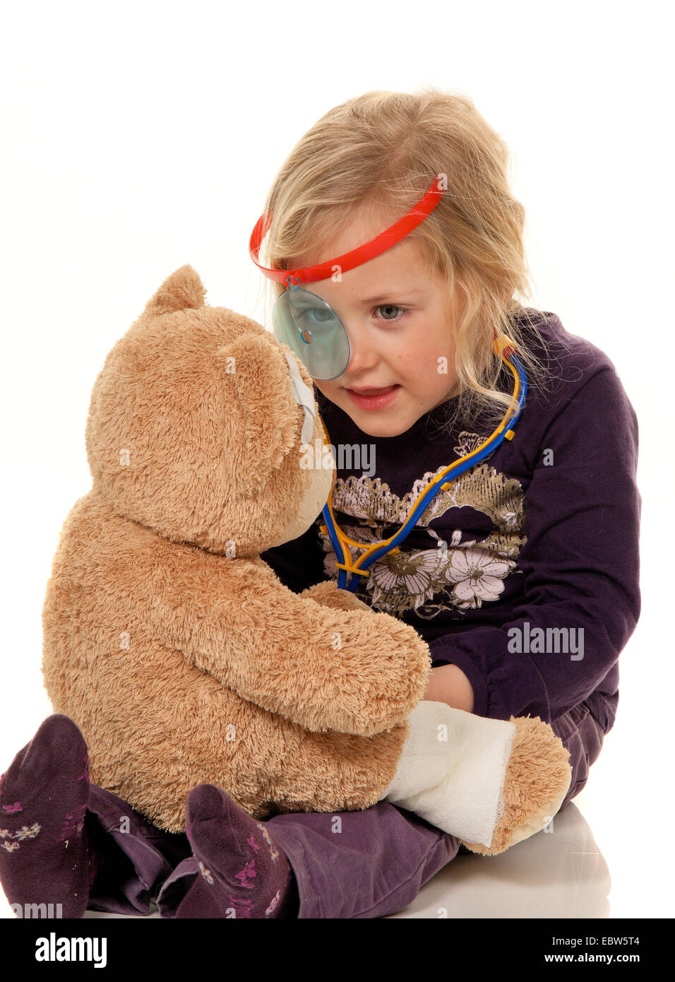 child with a stethoscope like a doctor, examines teddy Stock Photo