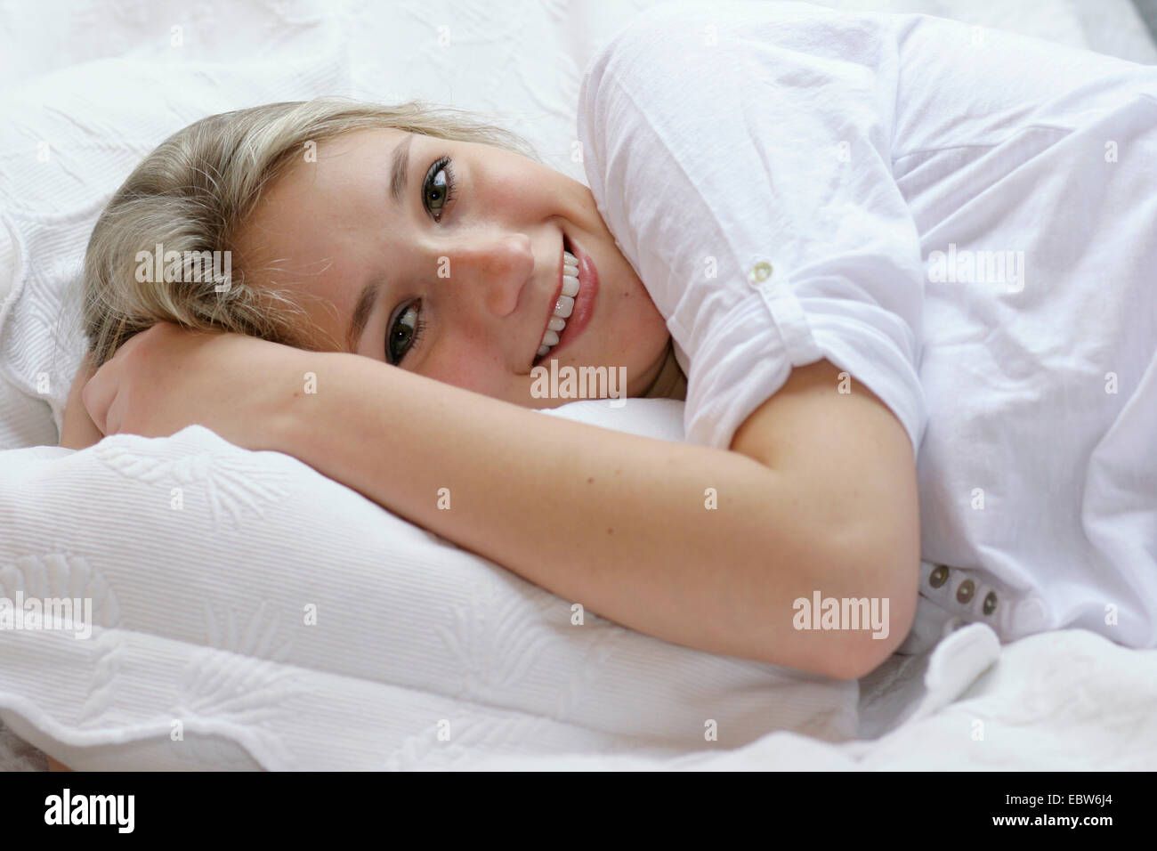 attractive young blond woman lying in bed Stock Photo