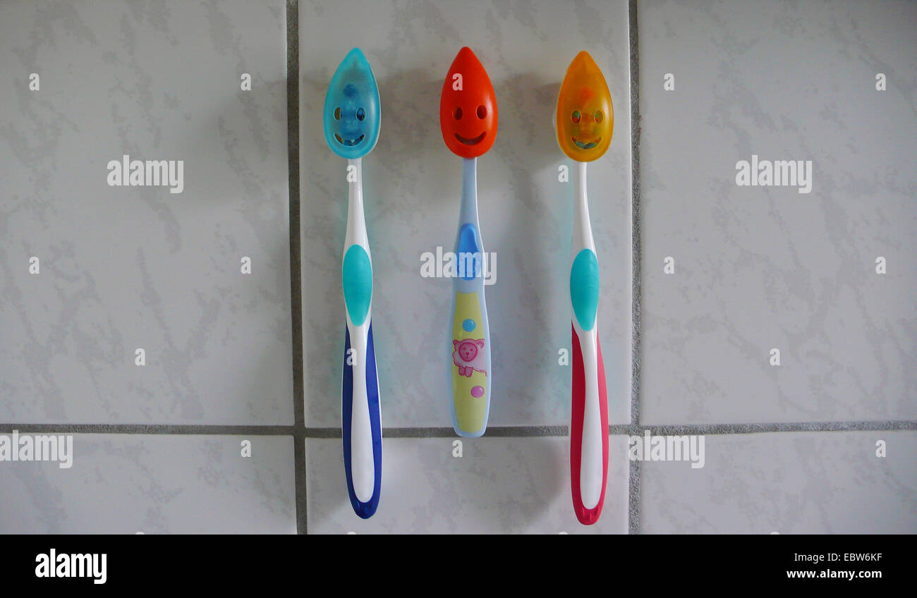 three toothbrushes of a family at tiles Stock Photo