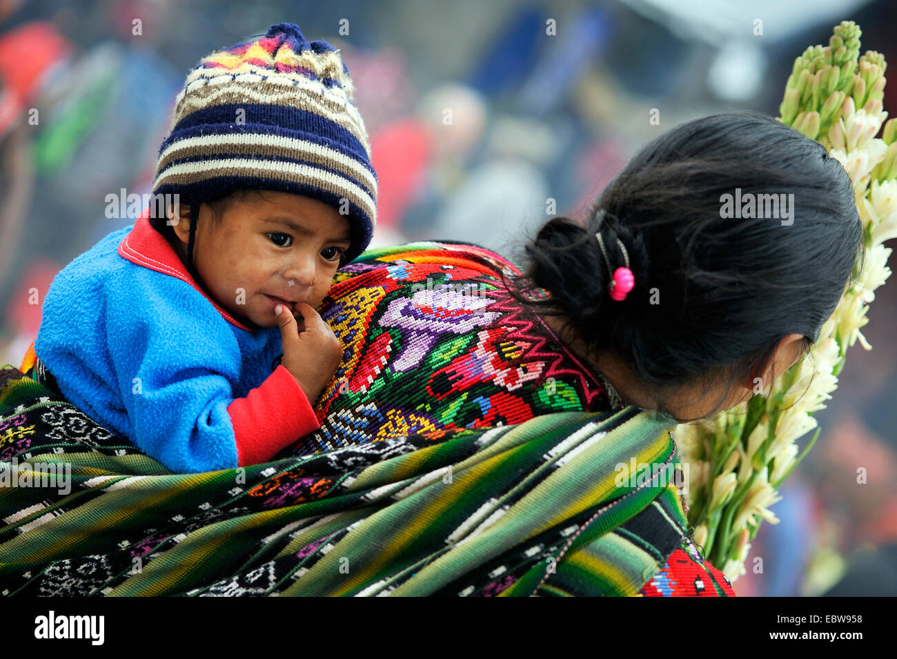 child on the back of the mother who is working in a field, Guatemala Stock Photo
