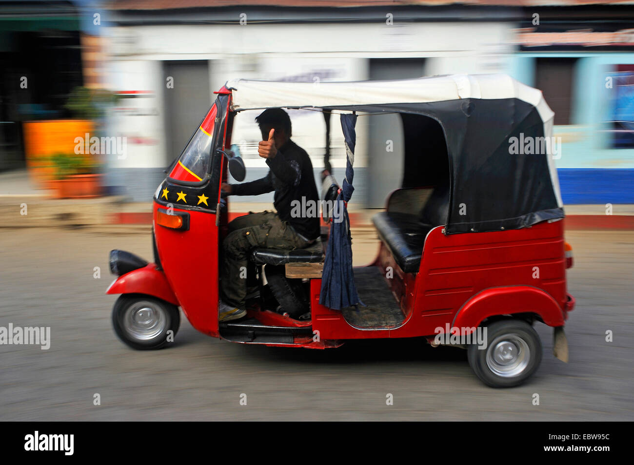 taxi driver passing in his auto rickshaw showing the thumb turned upwards, Guatemala, Atitlan lake, Santa cruz la Laguna Stock Photo