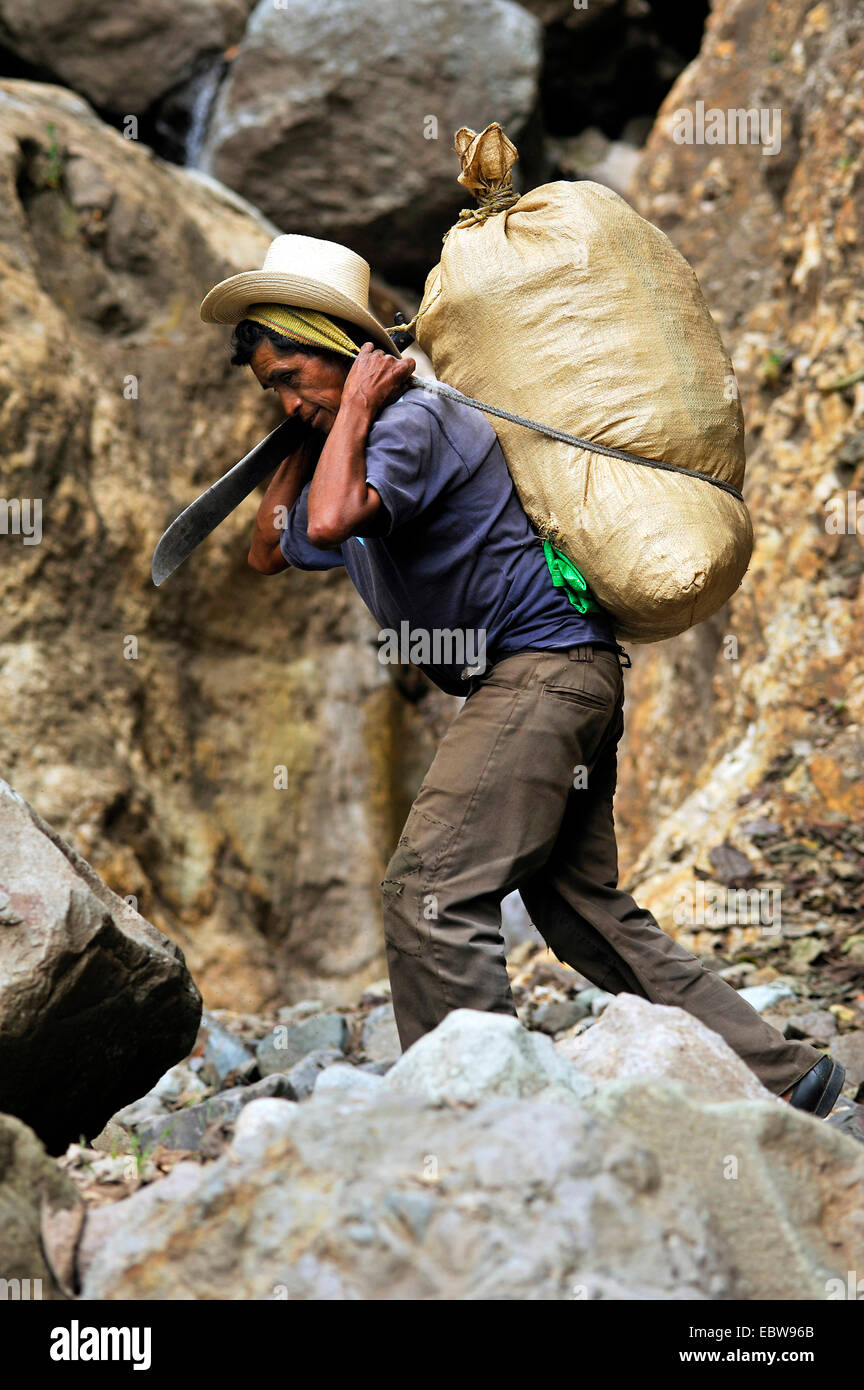 older man carrying a sack on his back over rocks with the help of a browband, Guatemala, Atitlan lake Stock Photo