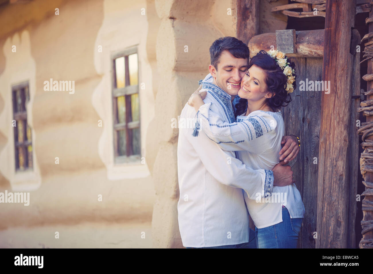 Young couple in Ukrainian style clothes standing at the entrance of rural house Stock Photo