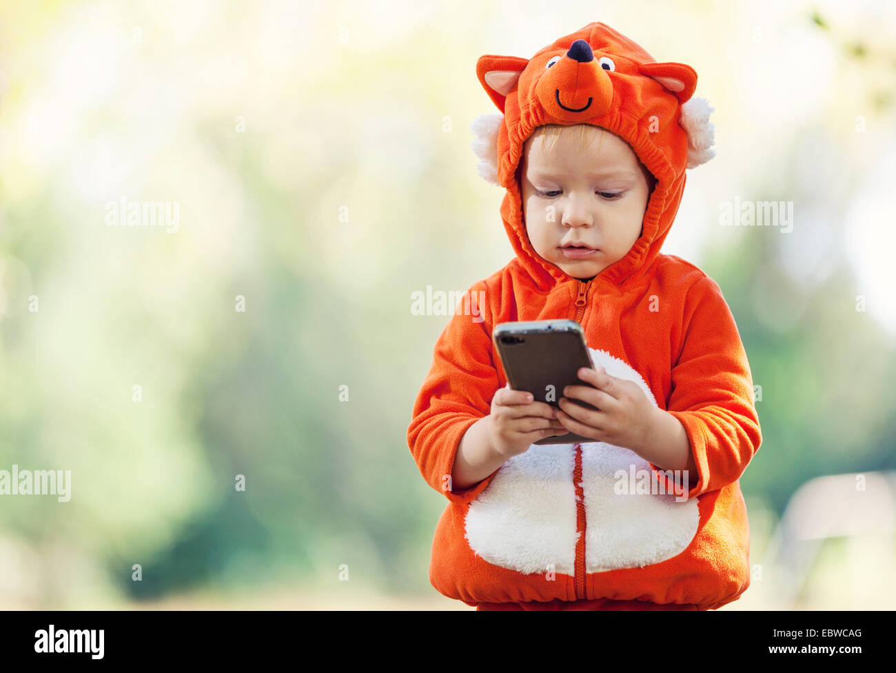 Joyful toddler boy in fox costume holding smartphone Stock Photo