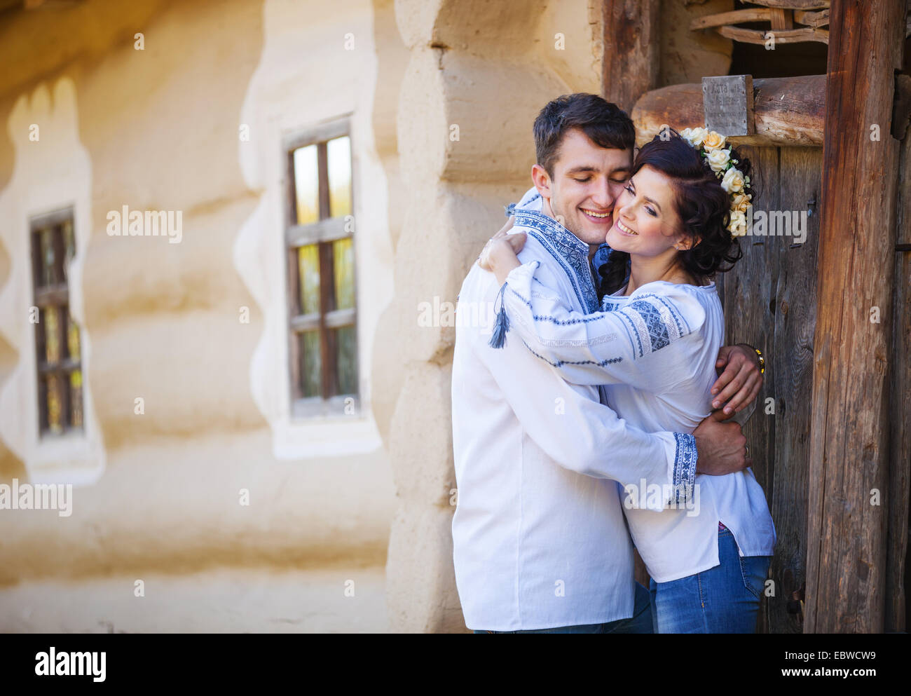 Young couple in Ukrainian style clothes standing at the entrance of rural house Stock Photo