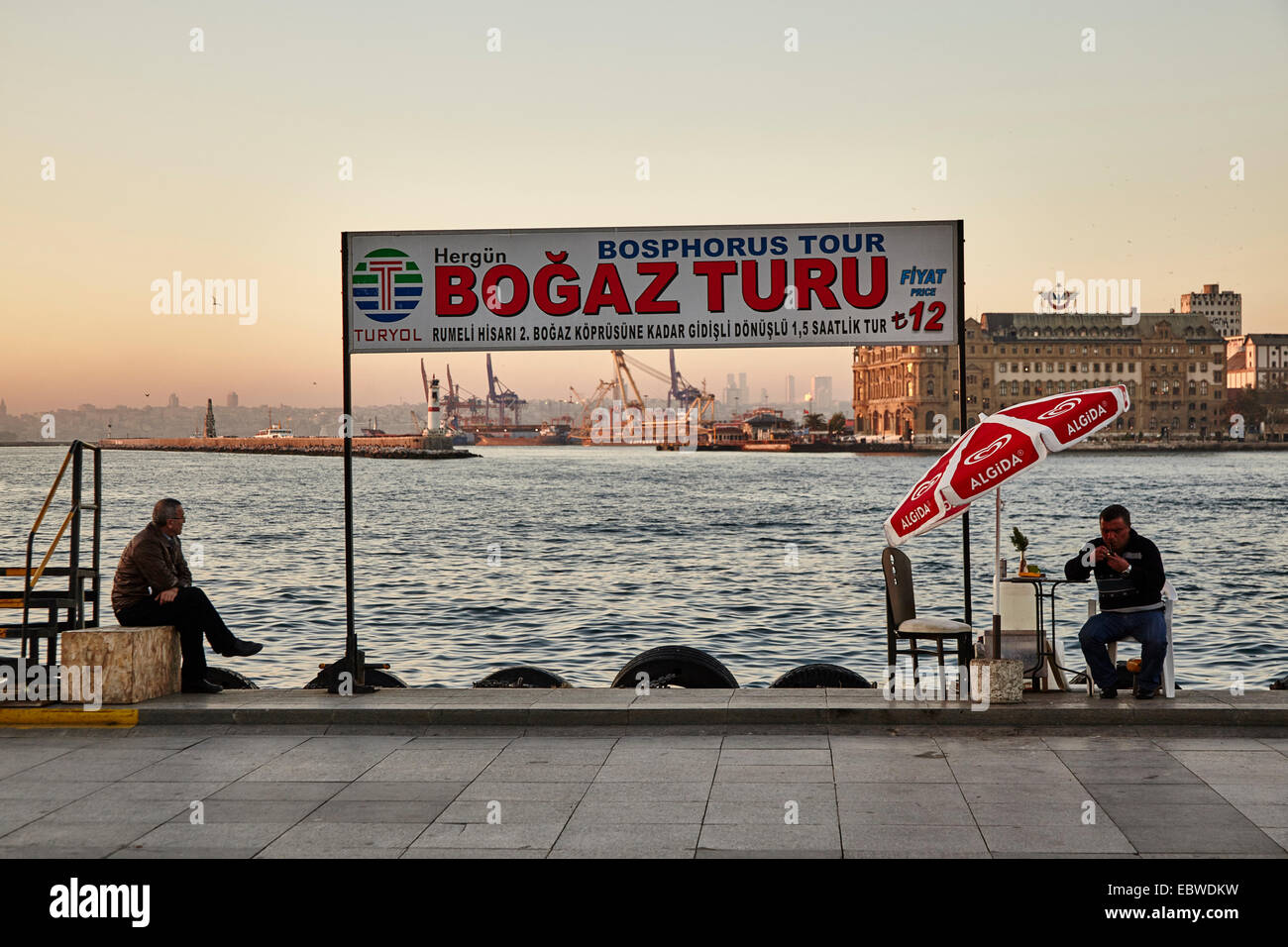 Two men sitting at Bosphorus Tour sign in Kadikoy no boat Stock Photo