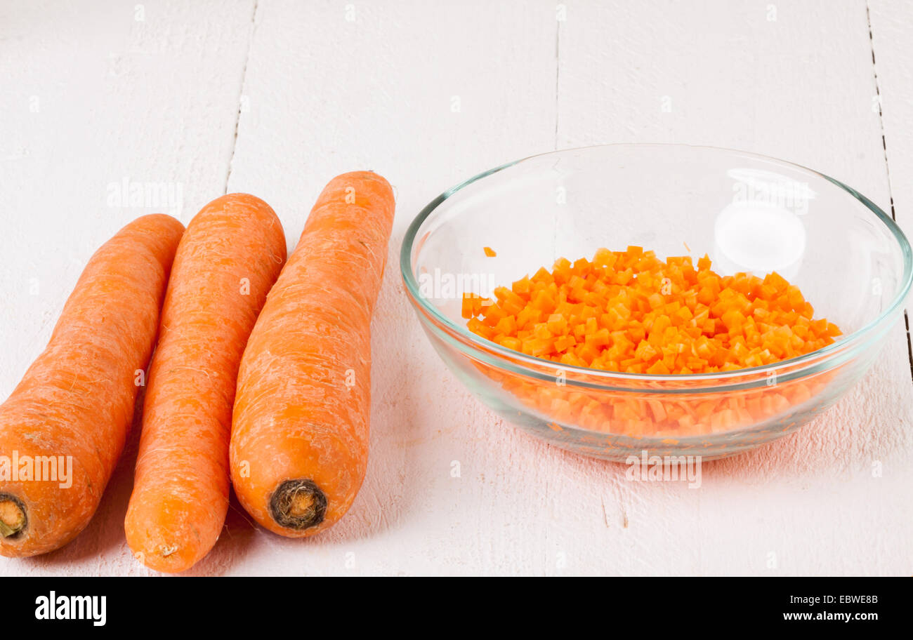Fresh peeled carrots sliced into thin batons for carrot julienne with a metal kitchen cutter on a white background Stock Photo