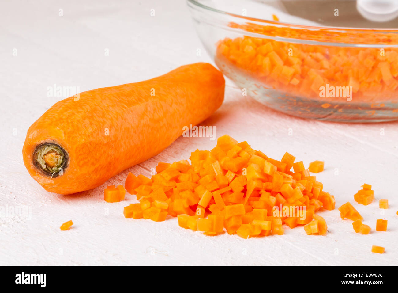 Fresh peeled carrots sliced into thin batons for carrot julienne with a metal kitchen cutter on a white background Stock Photo