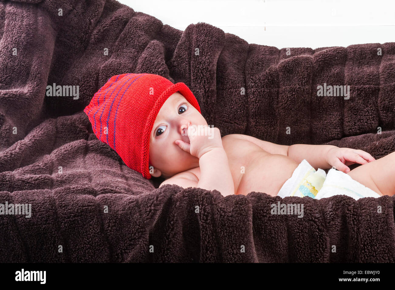 Surprising baby boy over brown blanket on white background Stock Photo