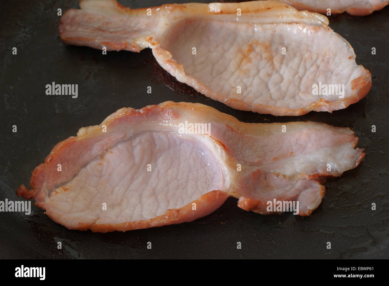 Frying pan with cooked bacon rashers on white background Stock Photo - Alamy