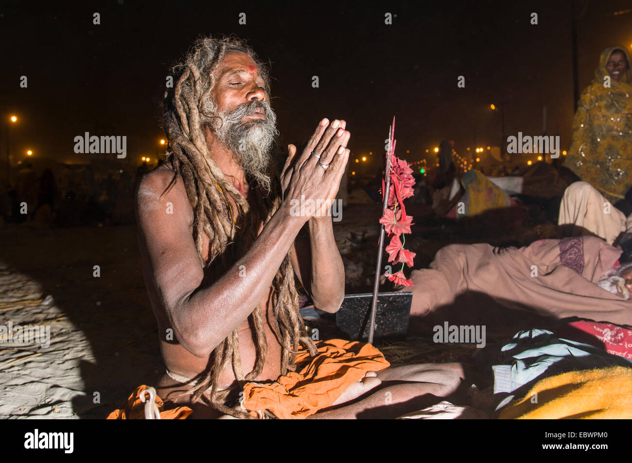 Shiva sadhu, holy man, sitting and praying at night at the Sangam, the confluence of the rivers Ganges, Yamuna and Saraswati Stock Photo