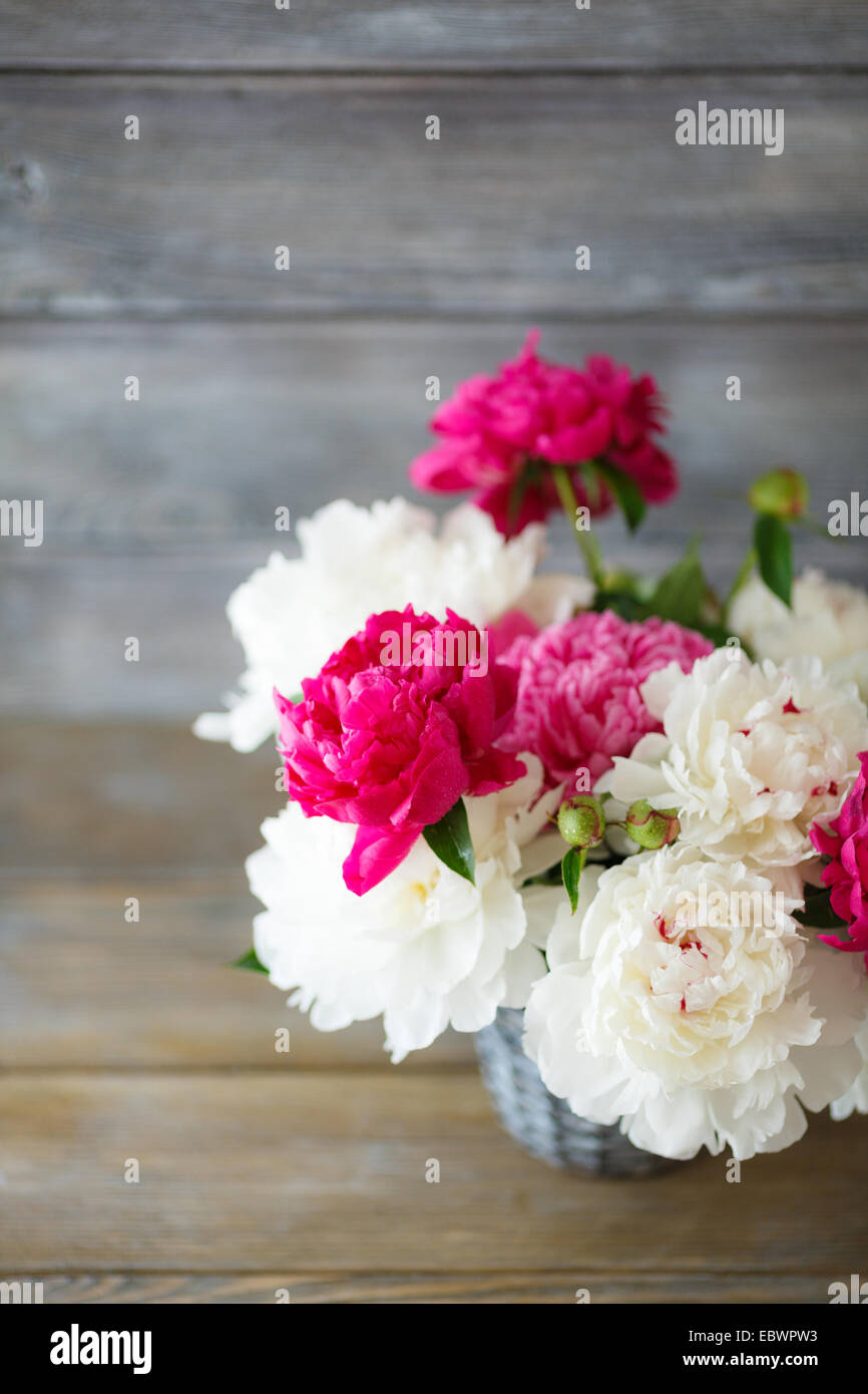 Peonies in a wicker vase on the boards, flowers Stock Photo