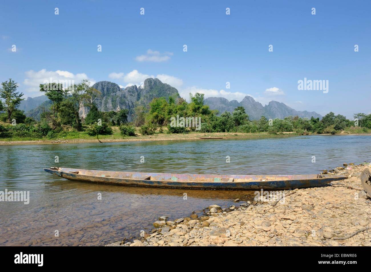Fishing boat on the Nam Khan River, karst mountains at back, near Vang Vieng, Vientiane Province, Laos Stock Photo