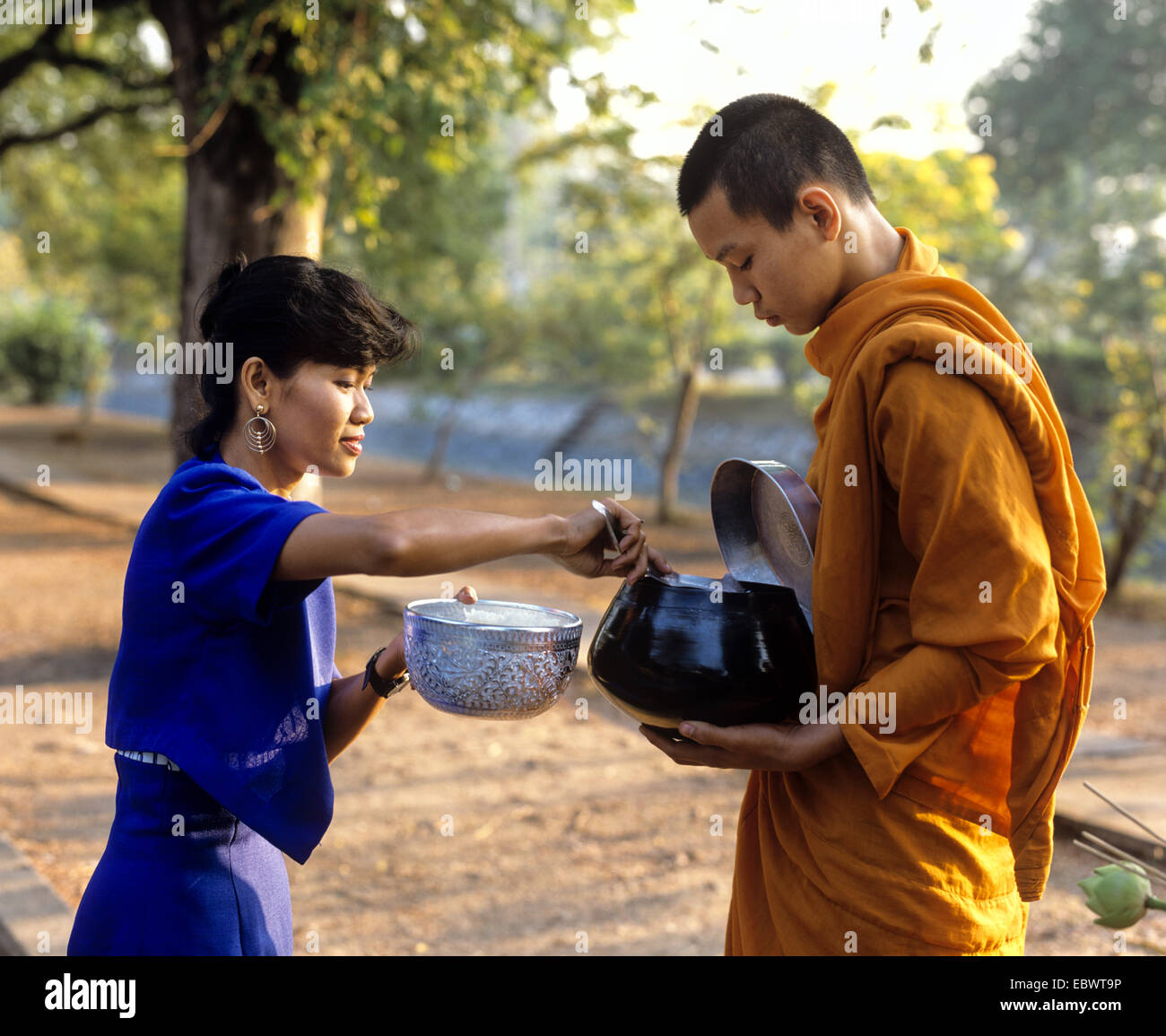 Begging monk, woman putting rice into the begging bowl of a Buddhist monk,  Mae Hong Son, Northern Thailand, Thailand Stock Photo - Alamy