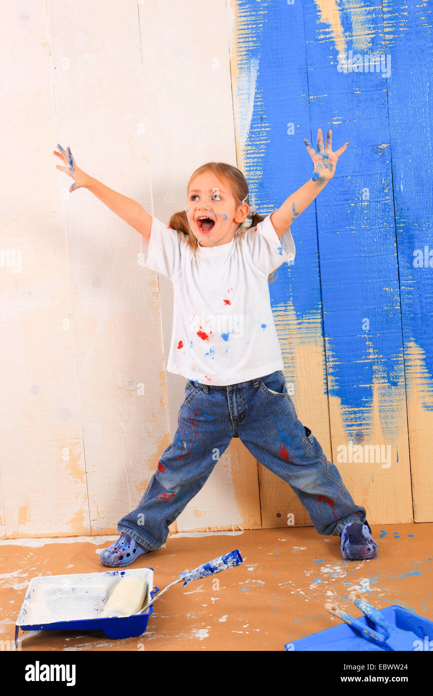 little girl standing in front of a wooden wall painted white and blue ...