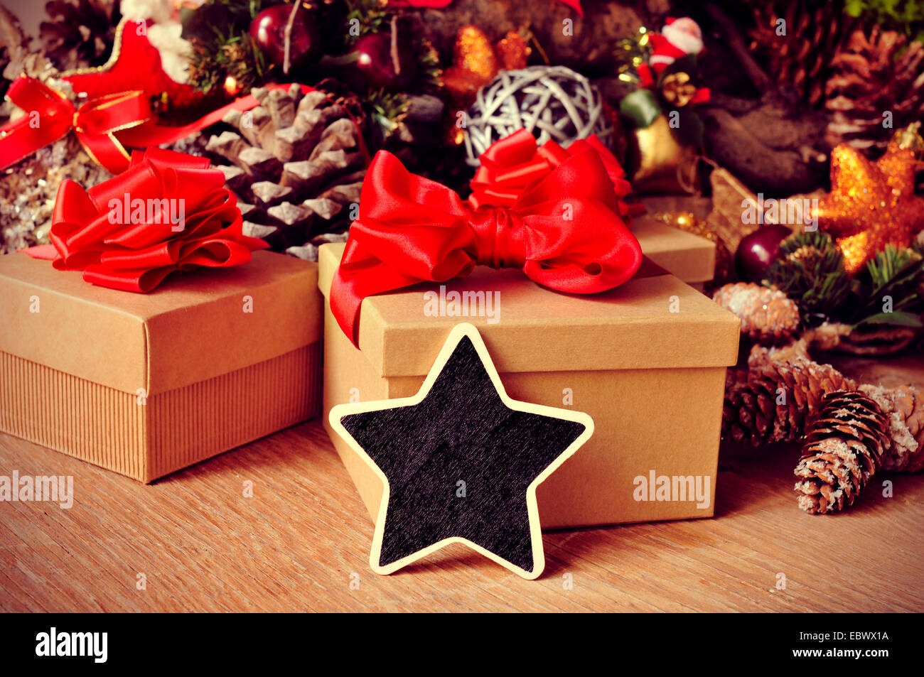 a blank star-shaped chalkboard on a rustic wooden table full of gifts and christmas ornaments, such christmas stars and pine con Stock Photo