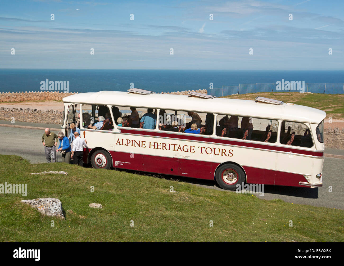 Heritage tour coach / bus with elderly passengers disembarking on Great Orme with blue ocean in background at Llandudno Wales Stock Photo