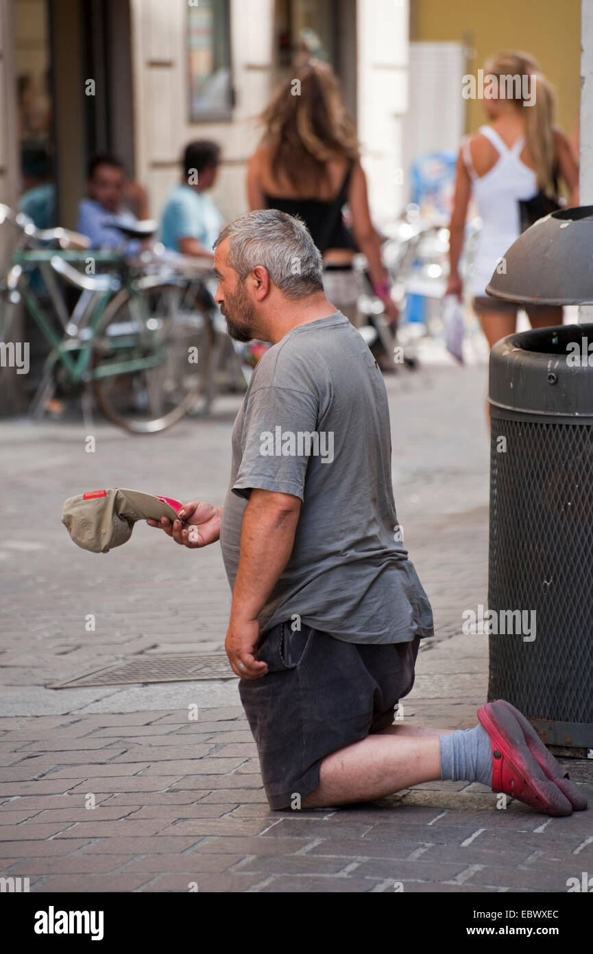 beggar kneeing on the ground, Italy, Lombardy Stock Photo