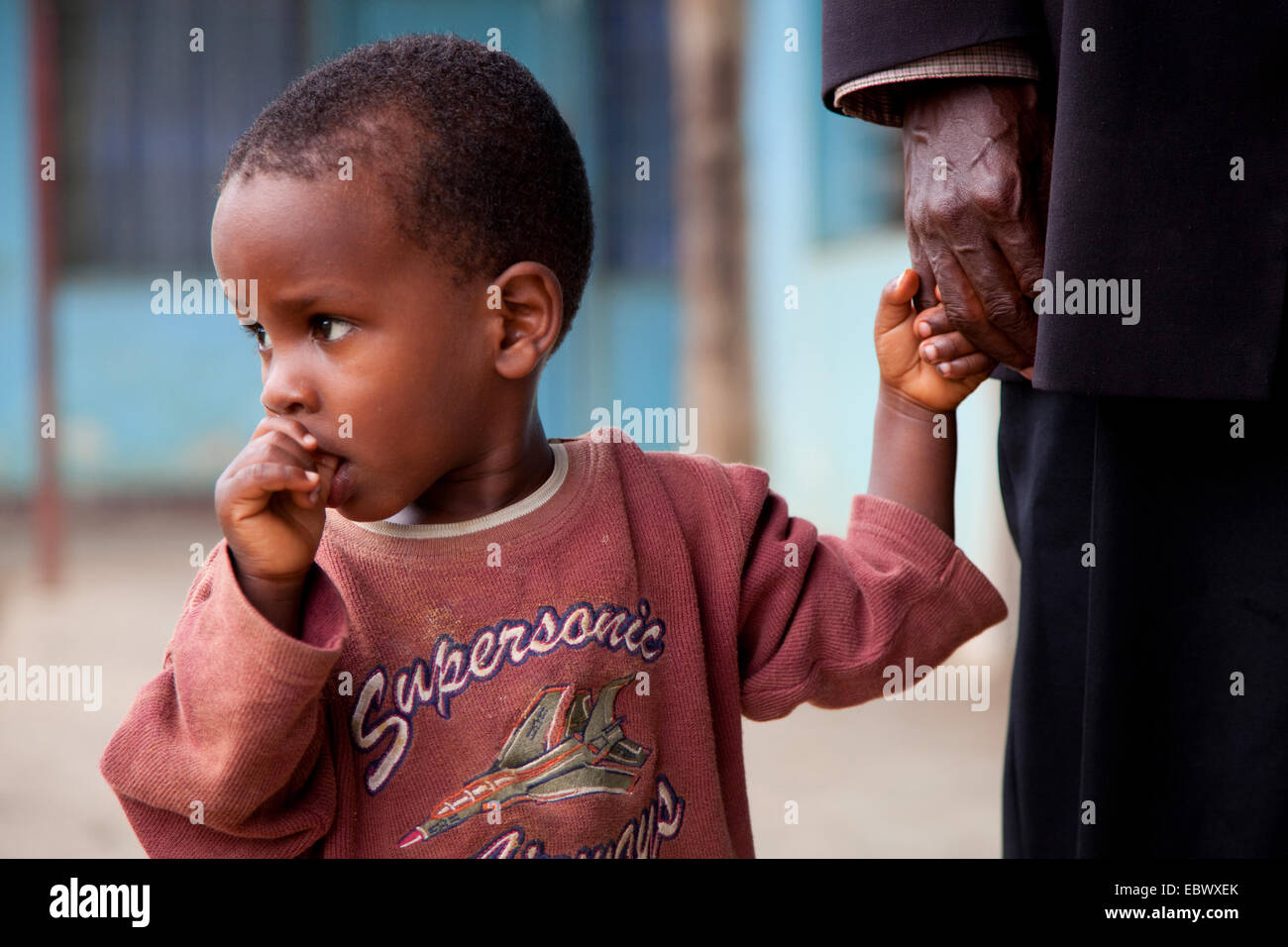little boy at an old man's hand is sucking on his thumb, Burundi, Bujumbura Marie, Bujumbura Stock Photo