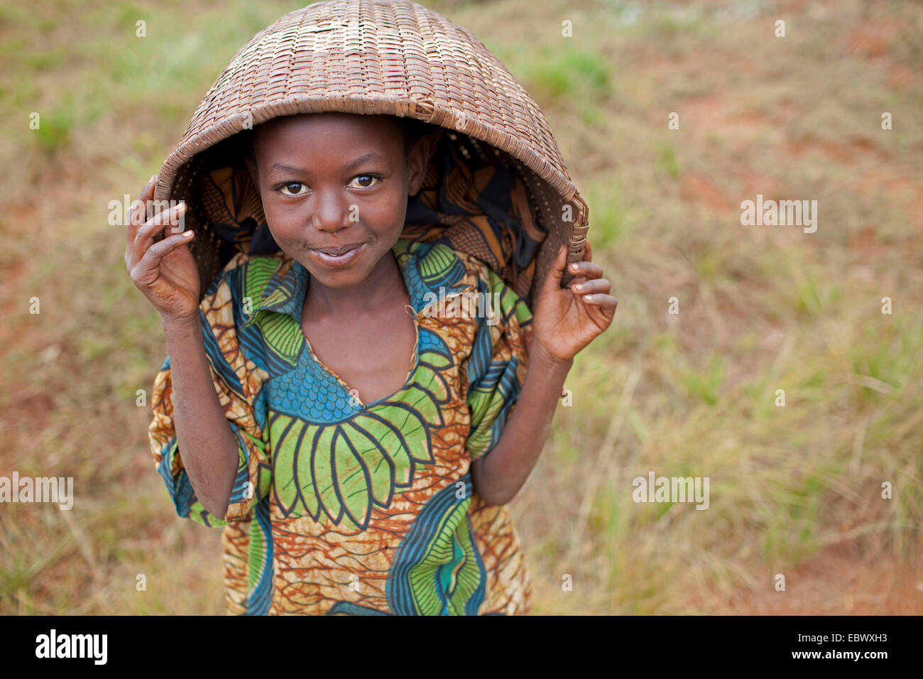 girl in traditional clothing holding basket above her head, Burundi, Karuzi, Buhiga Stock Photo