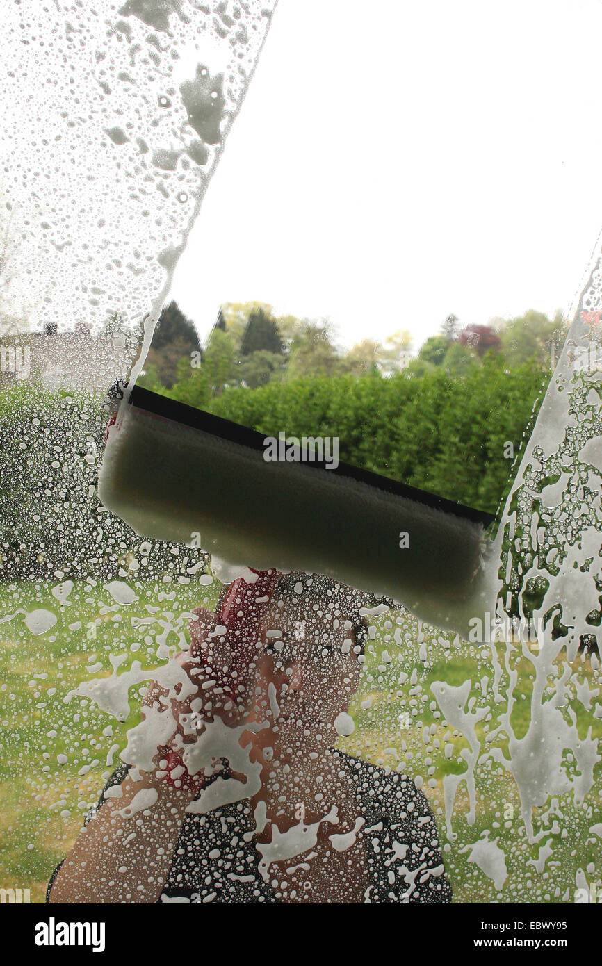 woman cleaning a window seen from inside Stock Photo