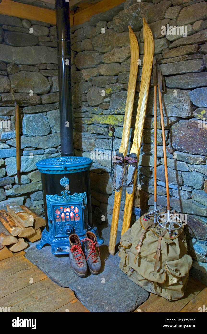 interior of a mountain hut with oven, backpack, and historical skis and si shoes, France Stock Photo