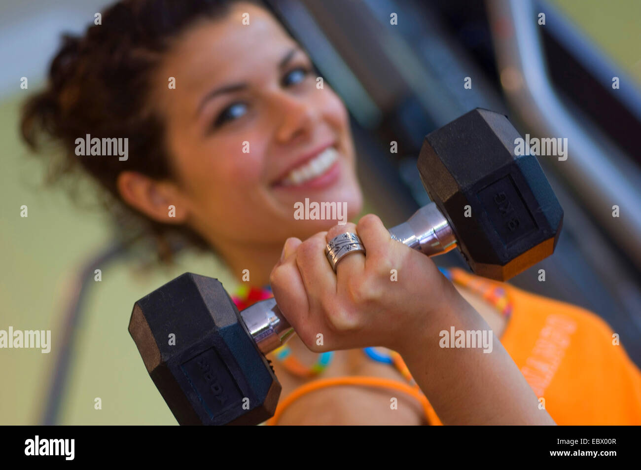 young woman in a fitness studio smiling during weight training Stock Photo