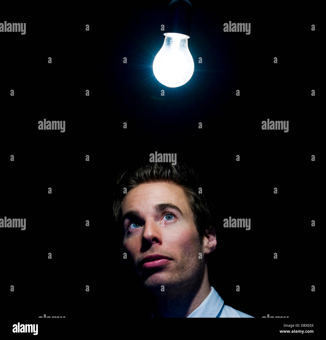 man looking at glowing light bulb Stock Photo Alamy