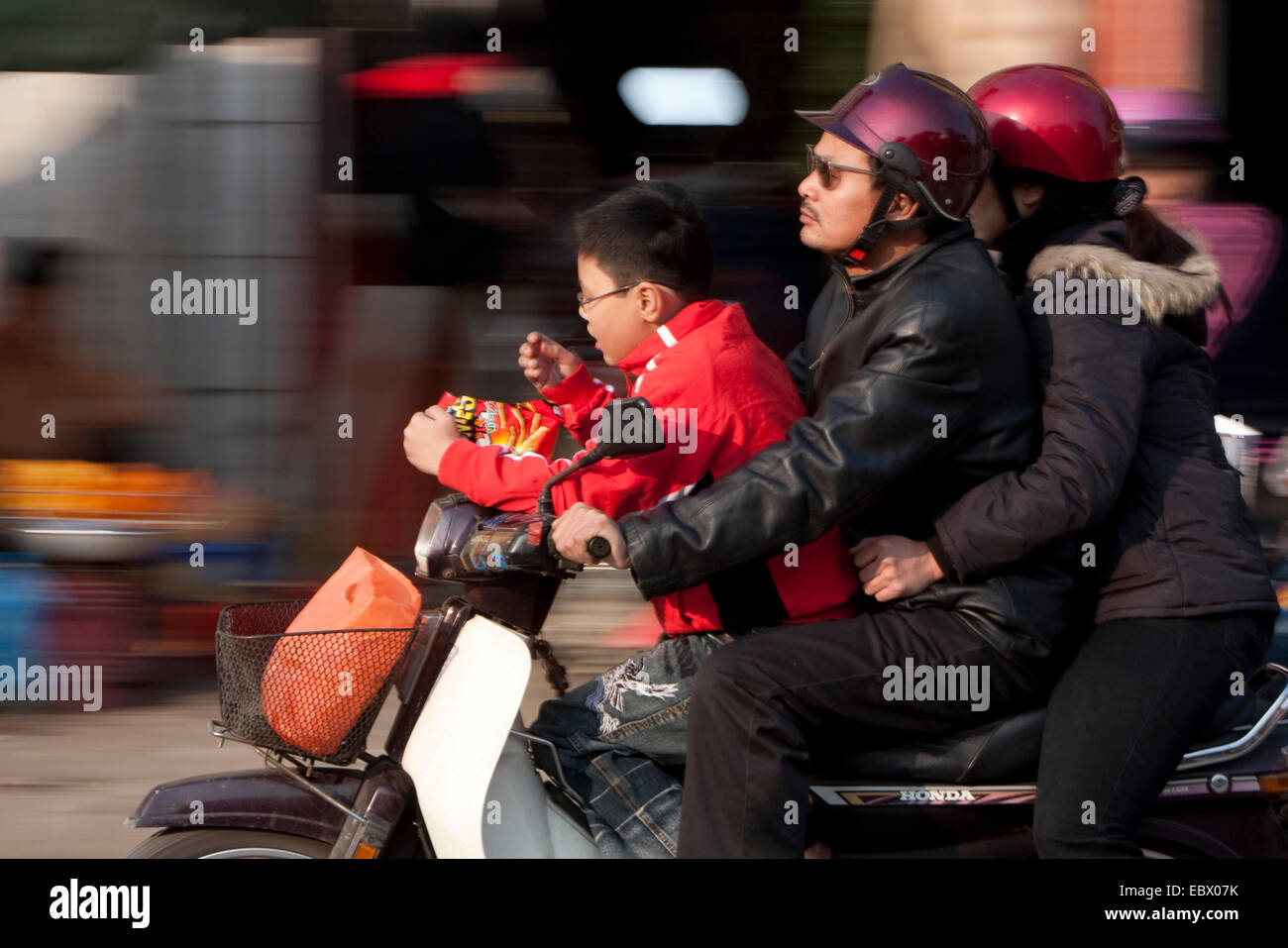 family riding through the city on a motor scooter, Vietnam, Hanoi Stock Photo