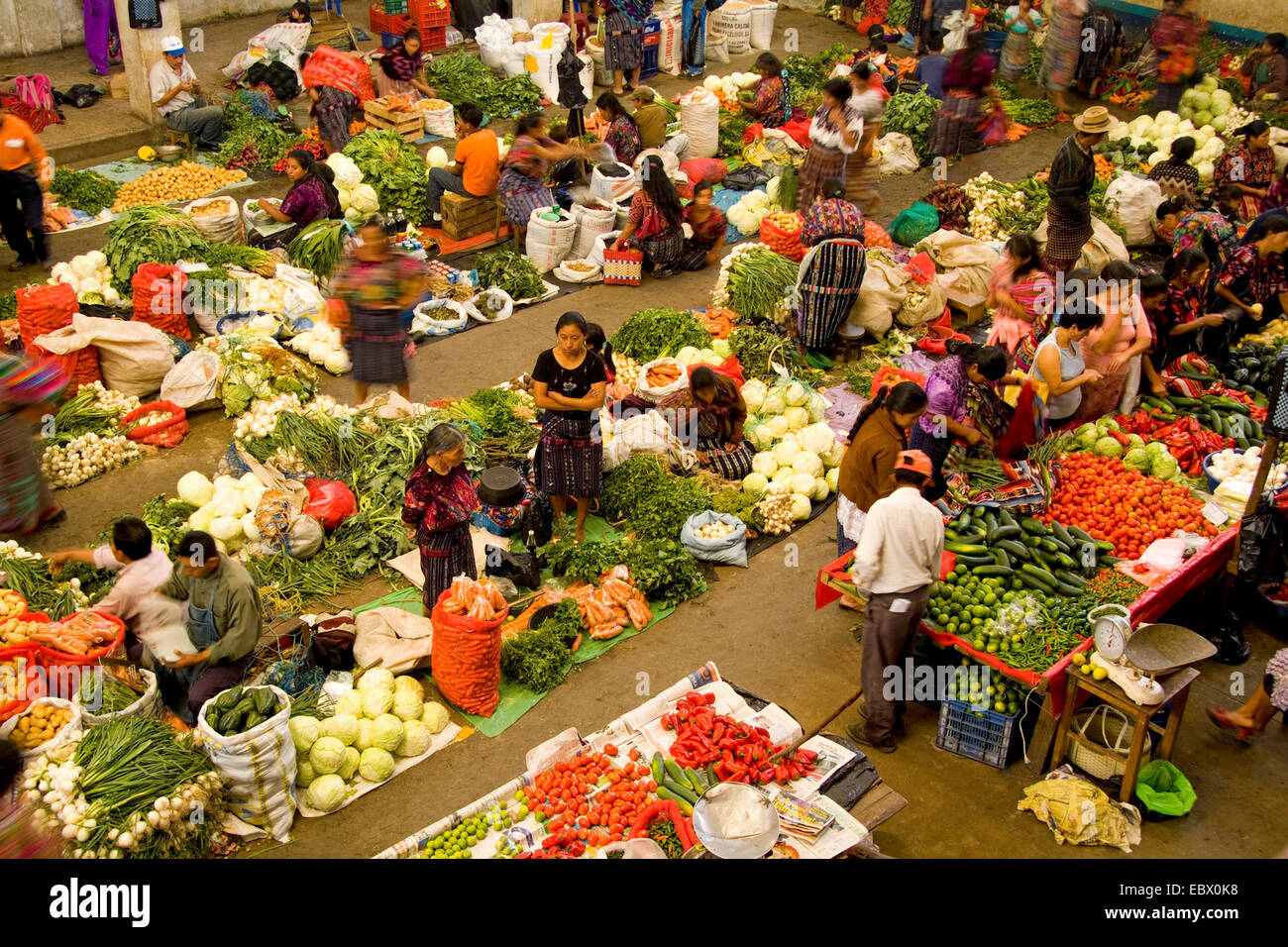 Local vendors in unusual birdseye angle from above with blurred movement in colorful printed clothes in fruit shopping center on market day, Guatemala, Chichicastenango Stock Photo
