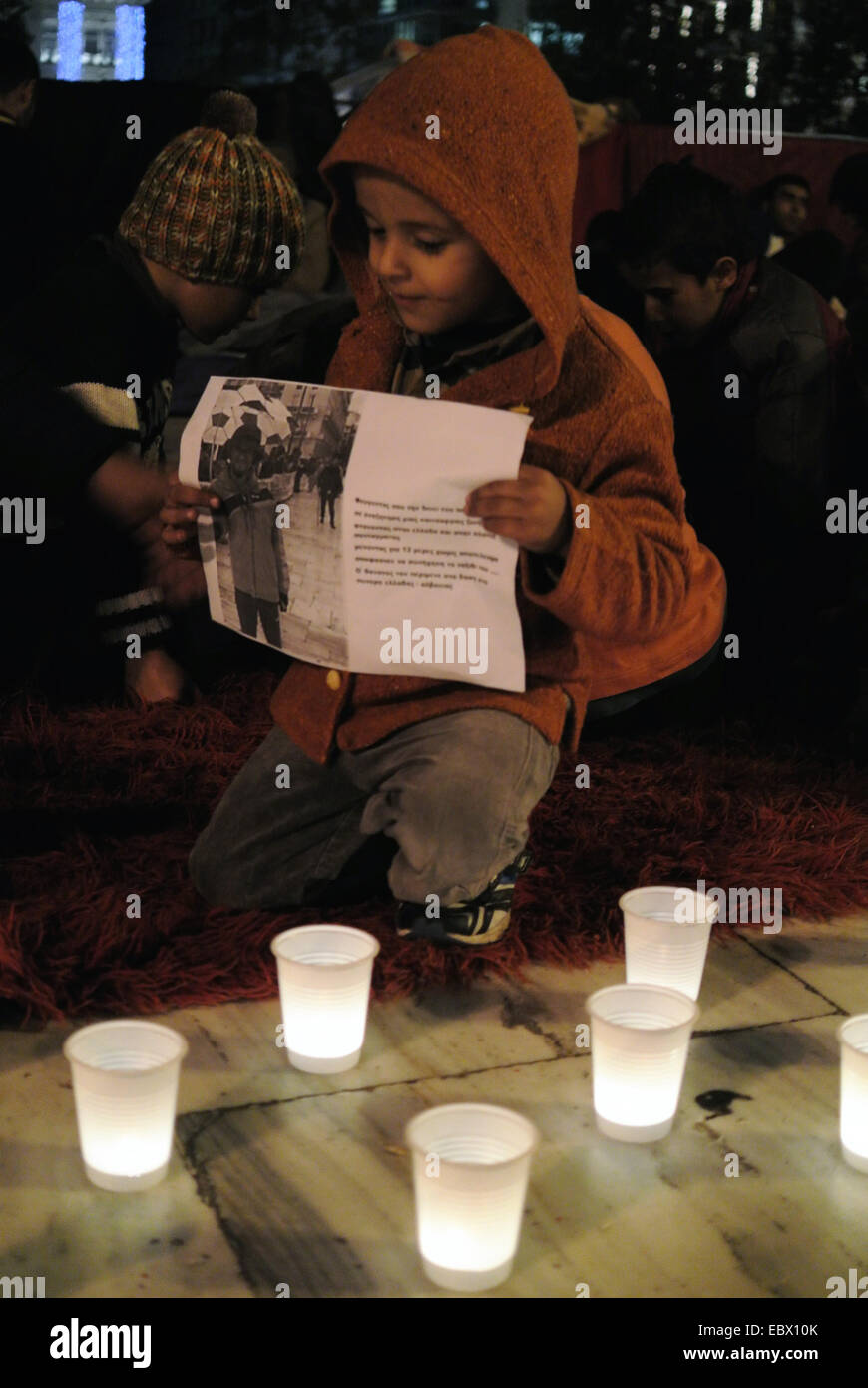 A young boy kneels behind lit candles. Syrian refugees that stay in