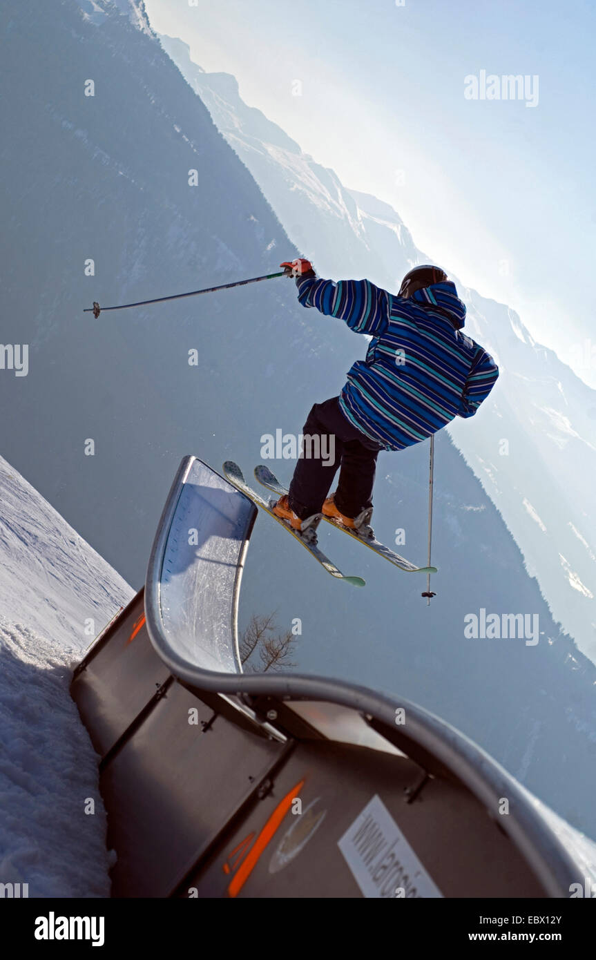 child with skis jumping over a small ski-jump Stock Photo