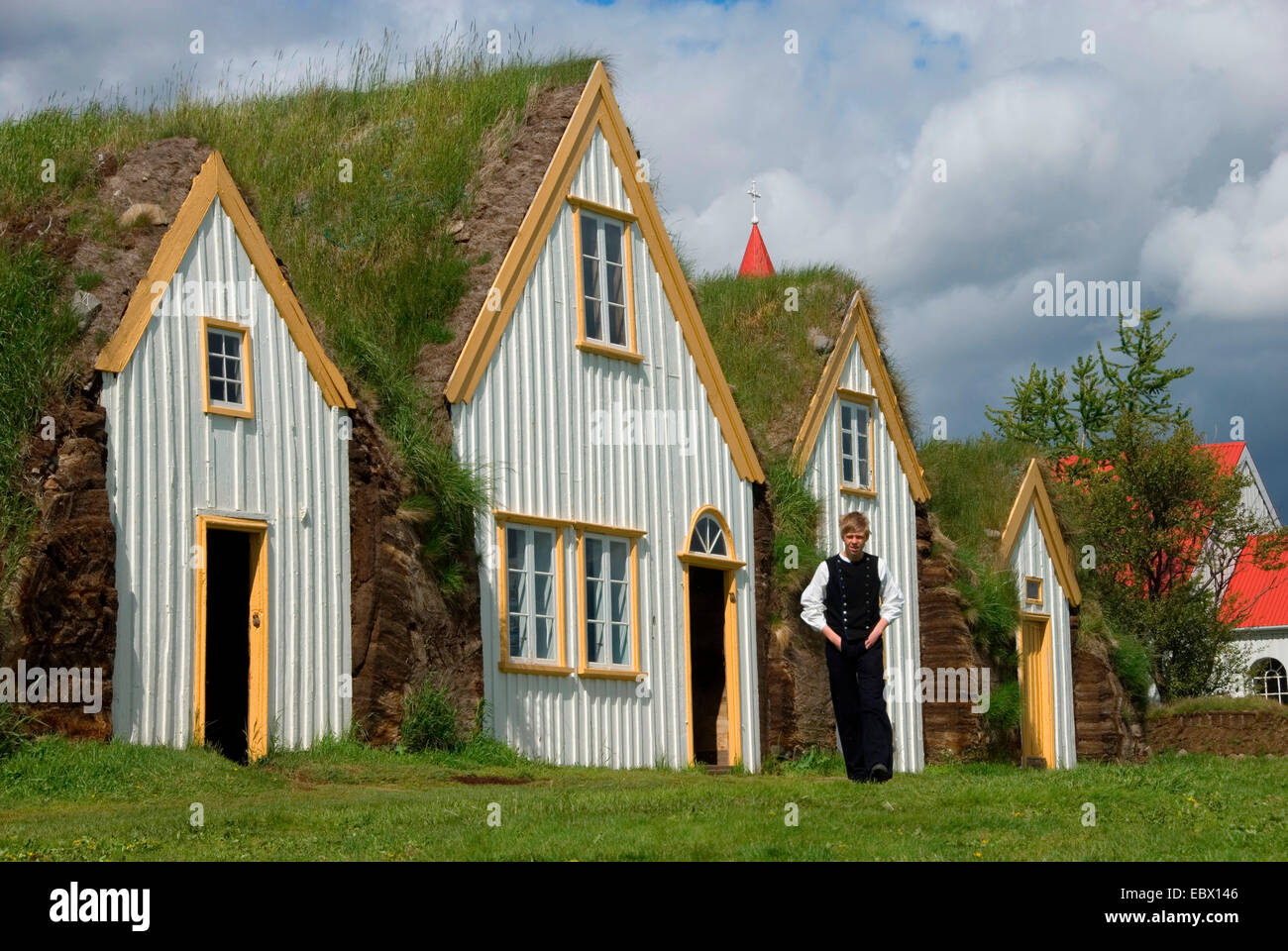 Junge in traditional dress peat houses in with grass roofs in open-air museums Glaumbaer, Iceland Stock Photo