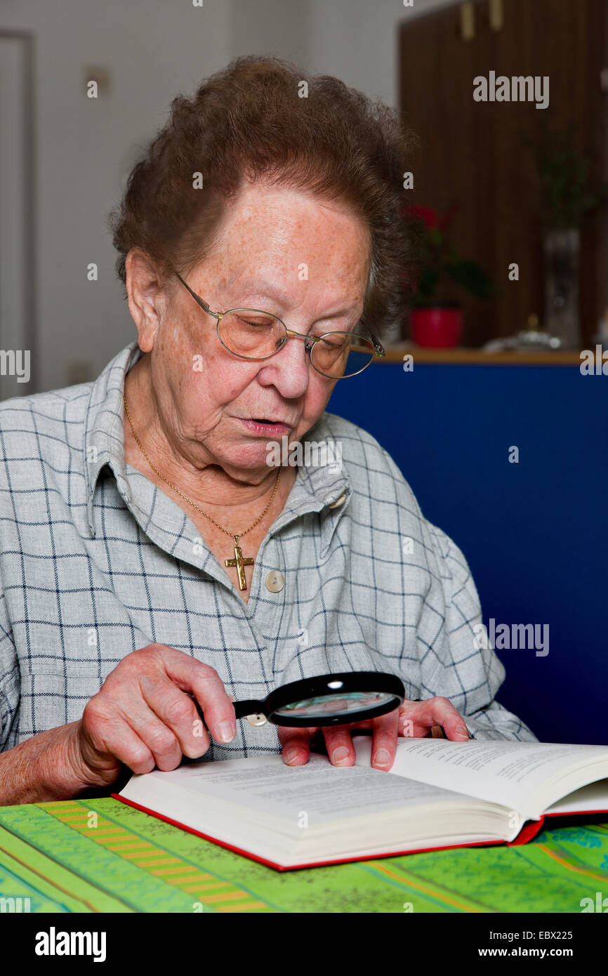 old Woman with glasses reading a book Stock Photo