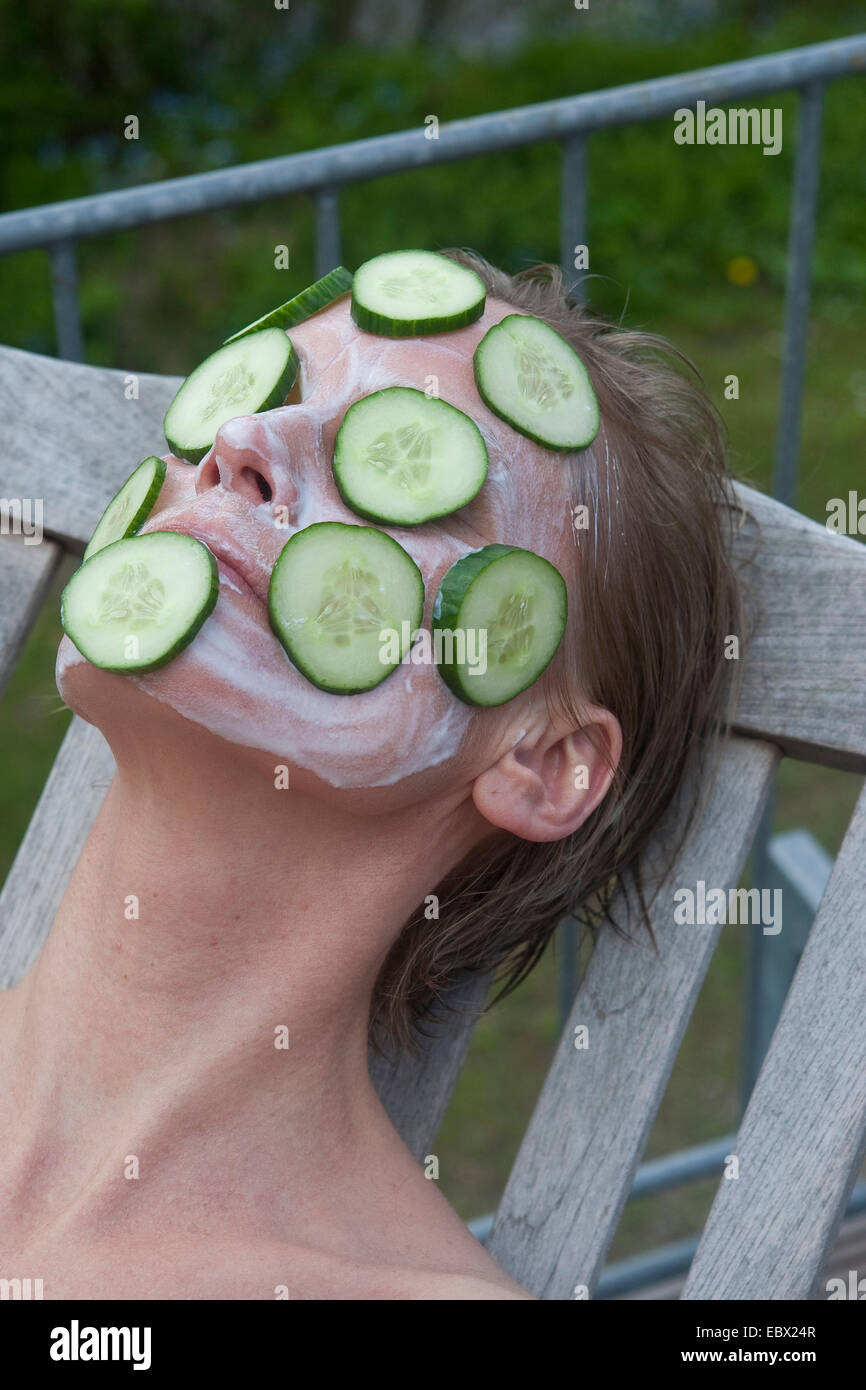 woman lying in a canvas chair with a cucumber mask Stock Photo