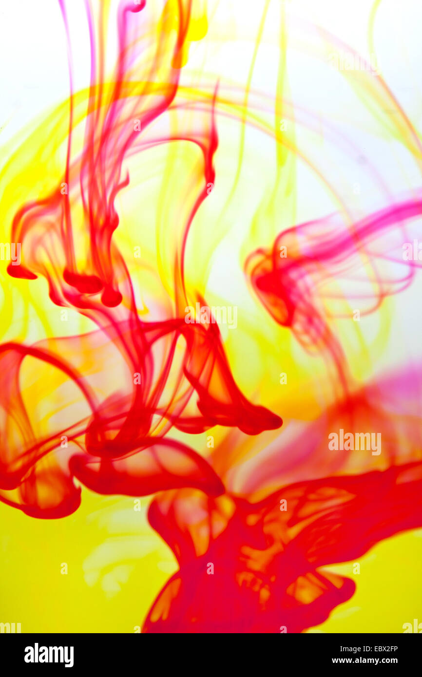 yellow and red color poured into water forming interesting streaks Stock Photo