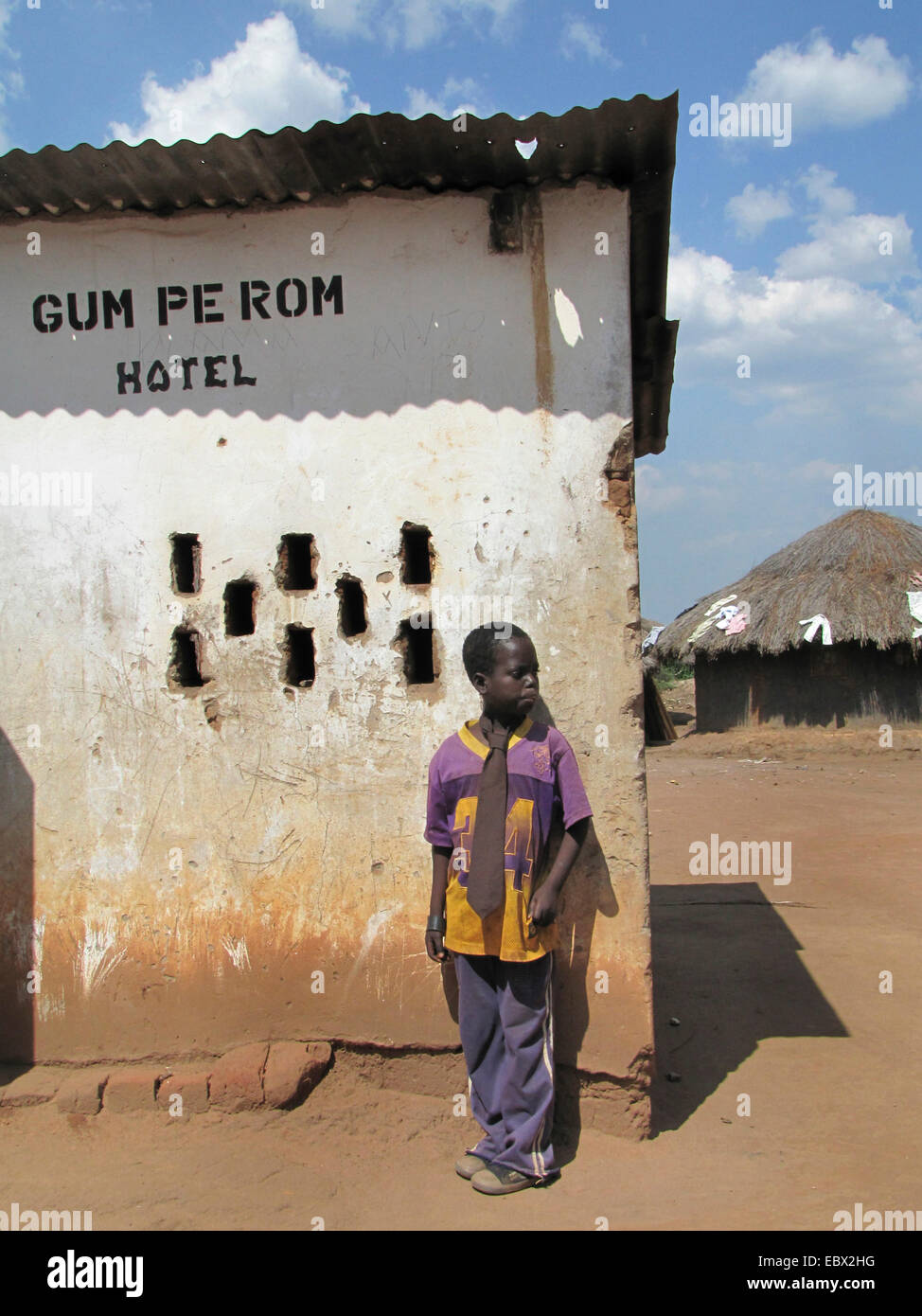 Refugee camp for internally displaced people in northern Uganda around Gulu, simple mud house in the background, boy standing next to a simple hotel, Uganda, Gulu Stock Photo
