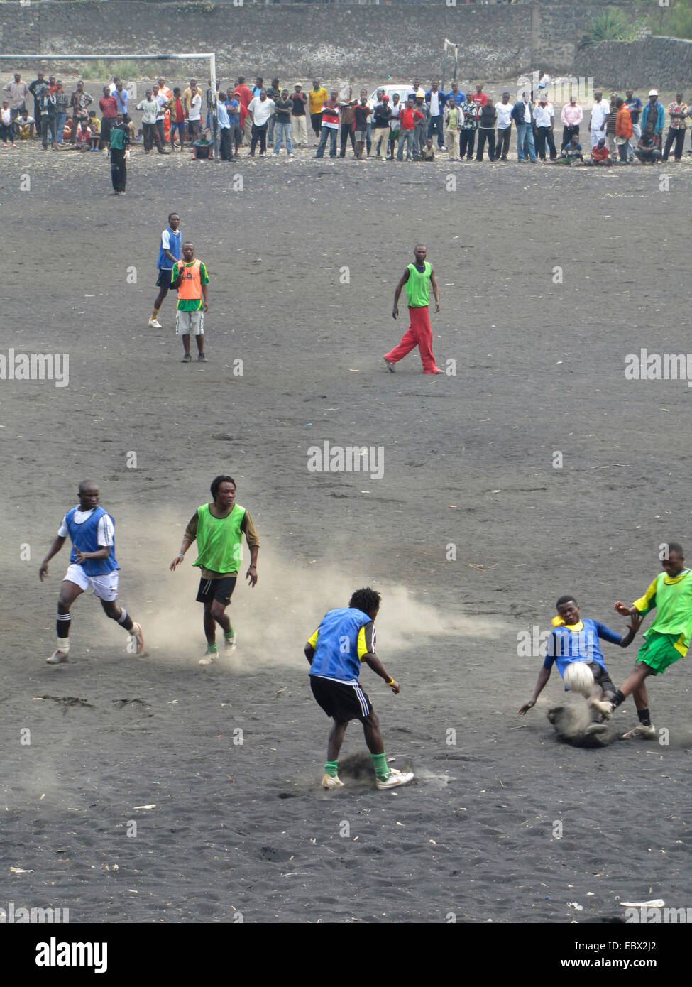 teenagers playing football on a football field with the ashes of the vulcano Nyiragongo, Republic of the Congo, North Kivu, Goma Stock Photo