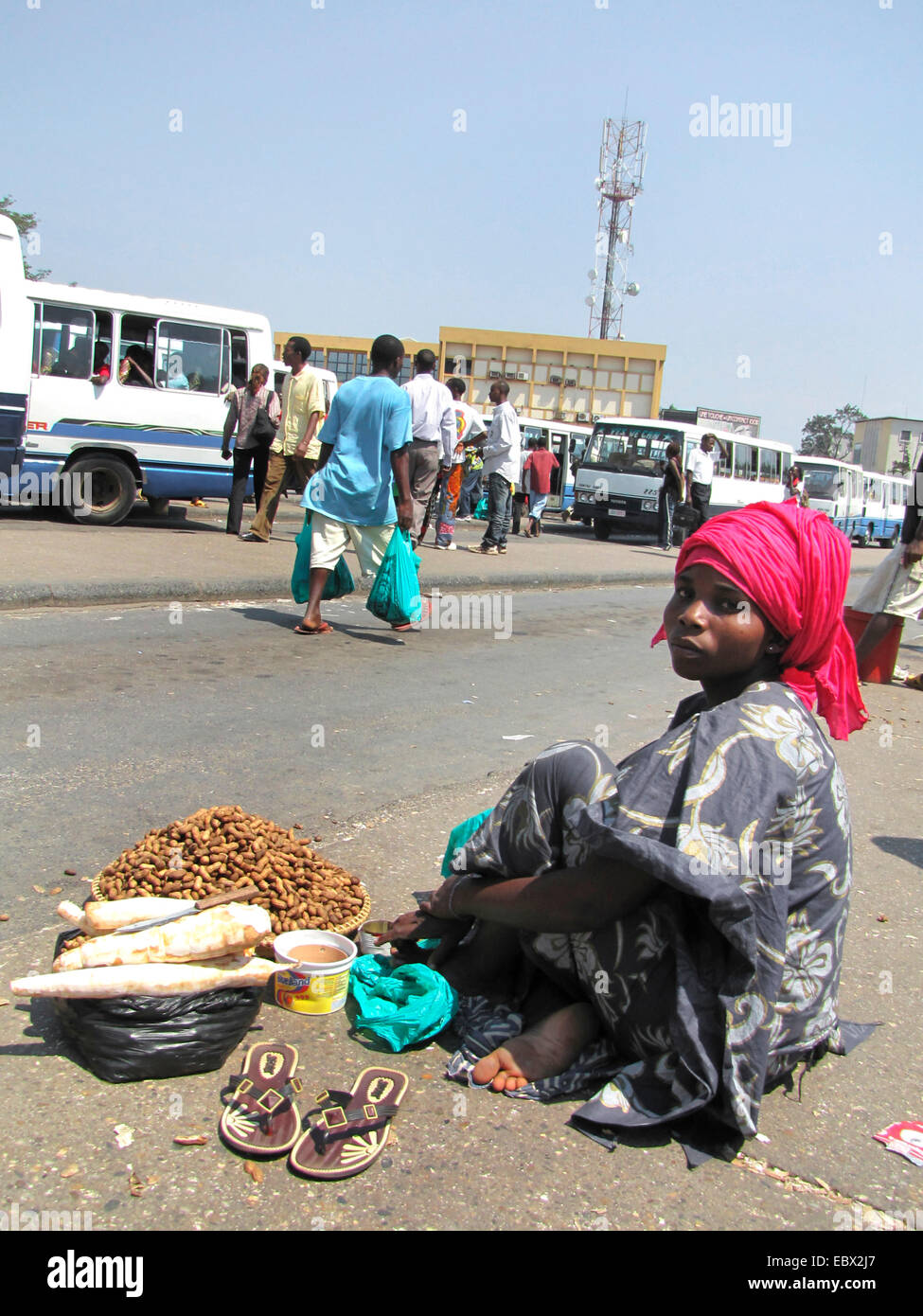 street scene in the capital city; young woman on the ground selling cassava and peanuts to passengers at the central bus station near the market, Burundi, Bujumbura marie, Bujumbura Stock Photo