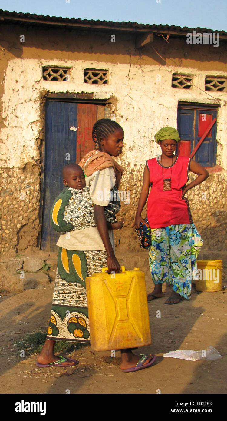 women at the poor area of the capital city taking water to their homes in canisters, baby is sleeping on its mother's back, Burundi, Bujumbura mairie, Buyenzi, Bujumbura Stock Photo