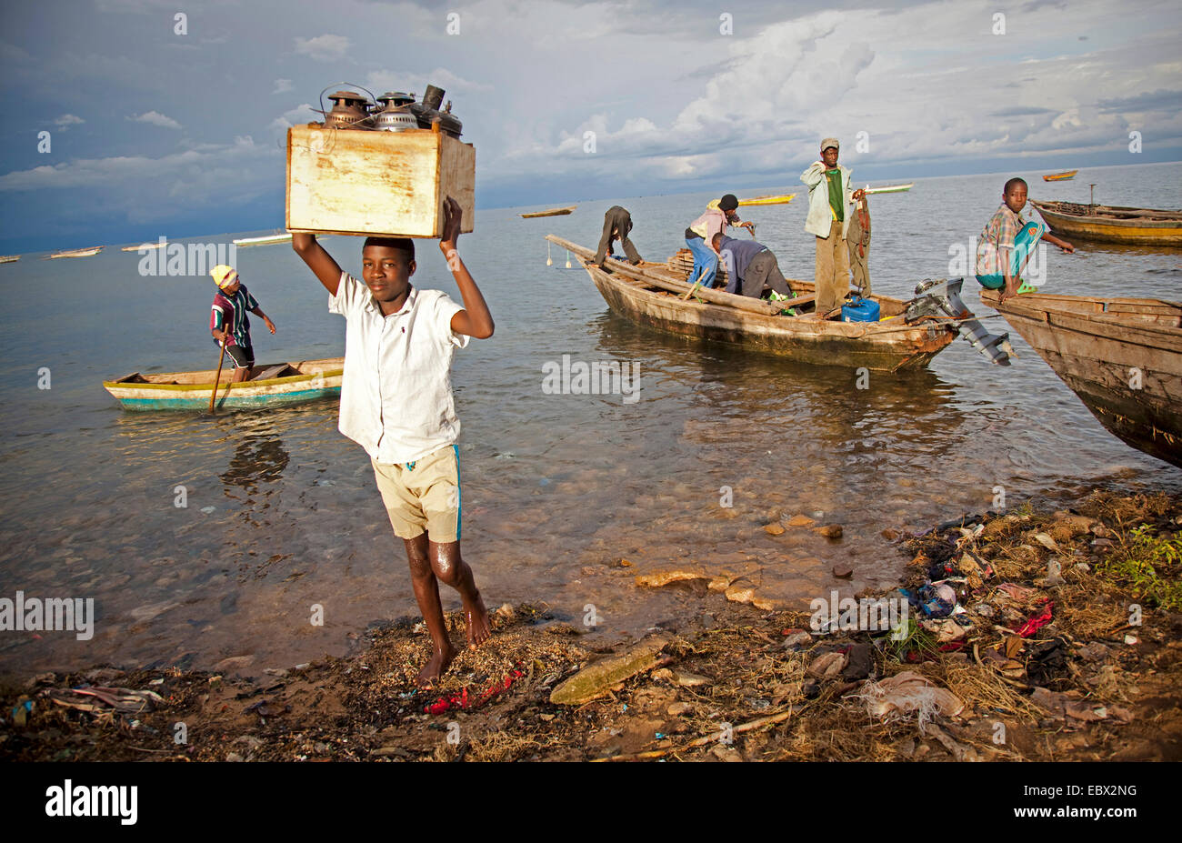 a boy carrying a box with oil lamps from fishing boat, Lake Tanganyika, Burundi, Makamba, Mvugo, Nyanza Lac Stock Photo