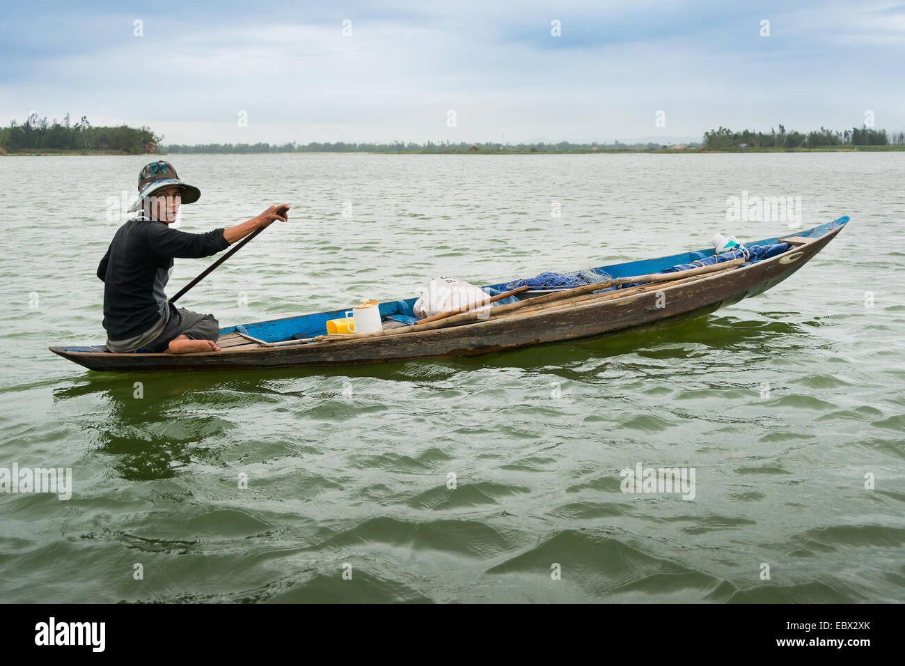 Vietnamese boatman paddling along Mekong Stock Photo