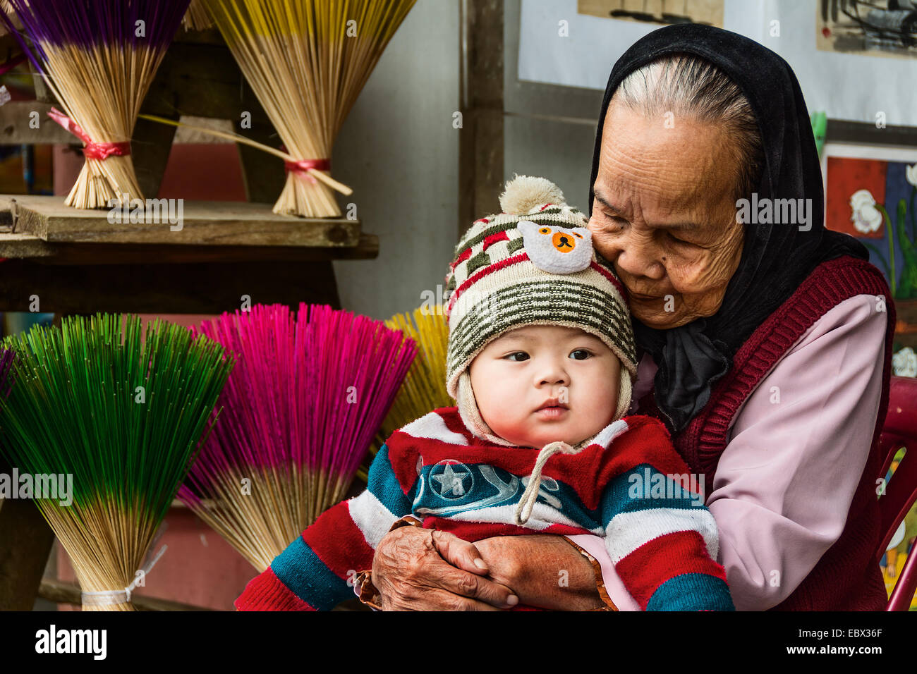 Vietnamese elderly lady with young child seated on her lap. Stock Photo