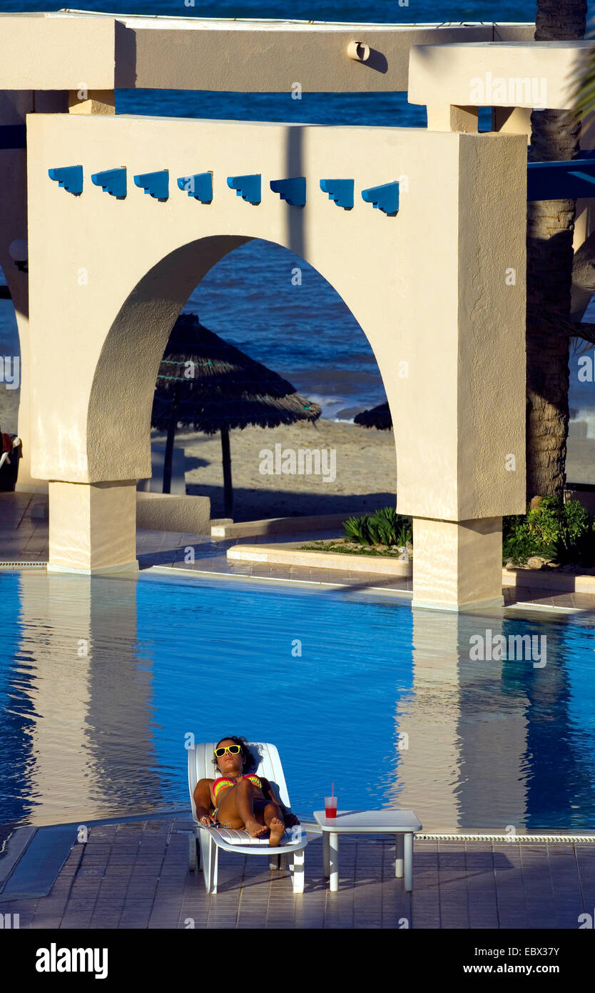 young woman taking a sunbath at the swiming pool of a luxurious hotel, Tunisia, Djerba Stock Photo