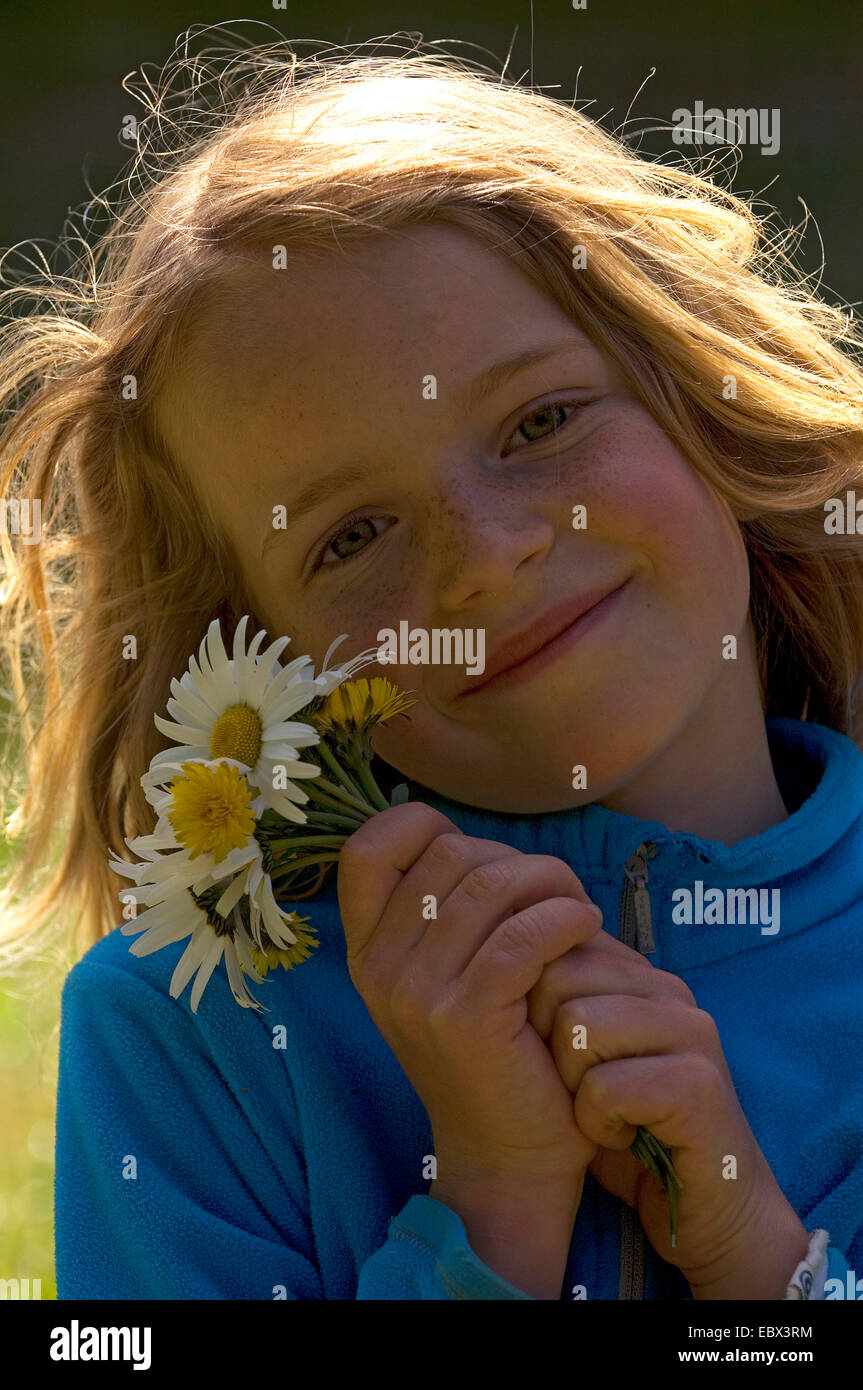 portrait of a smiling 8 year old girl with a bunch of daisies in hand, France Stock Photo