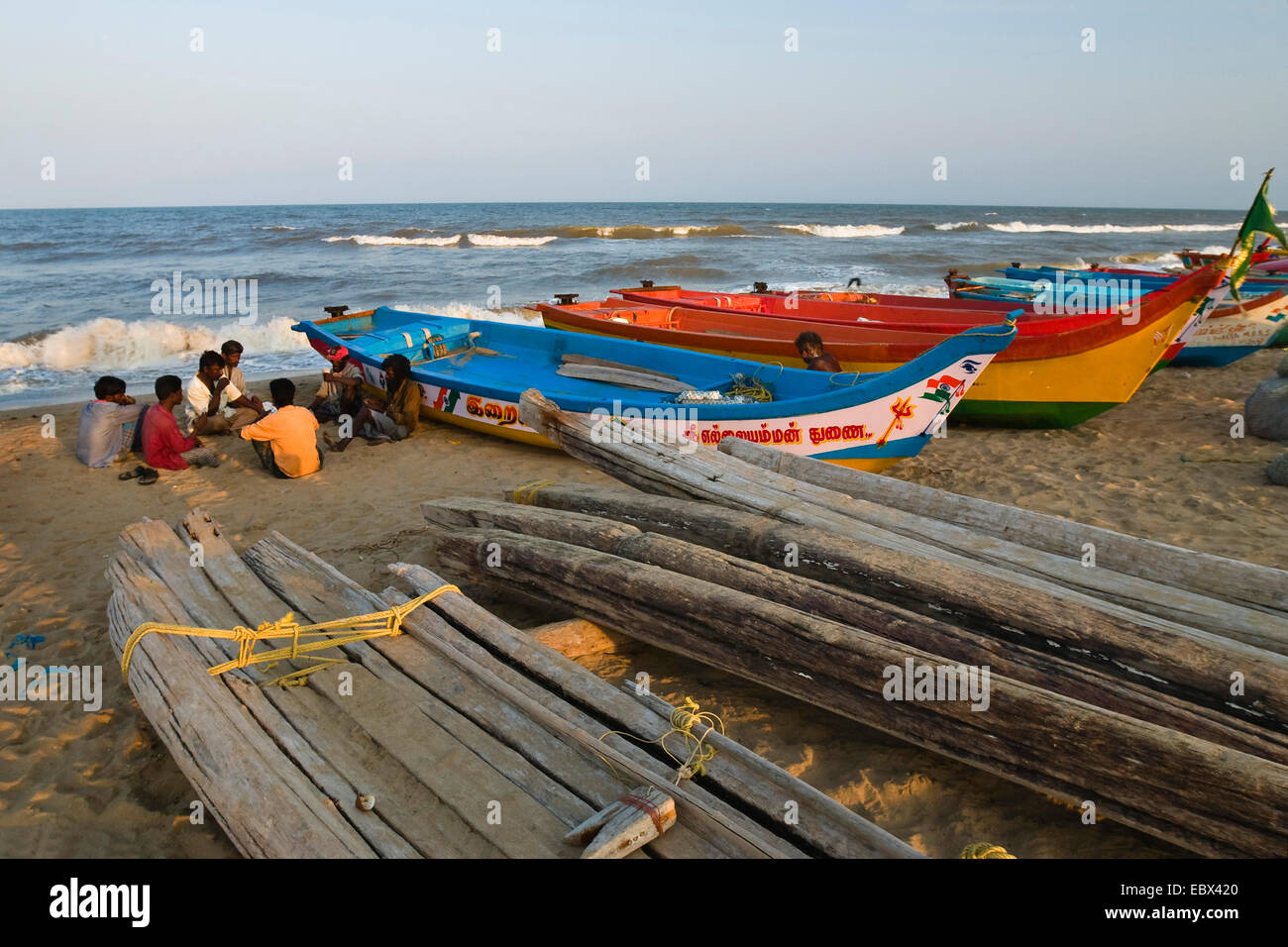fishermen sitting on sand beach beside their boats, India, Tamil Nadu, Marina Beach, Chennai Stock Photo