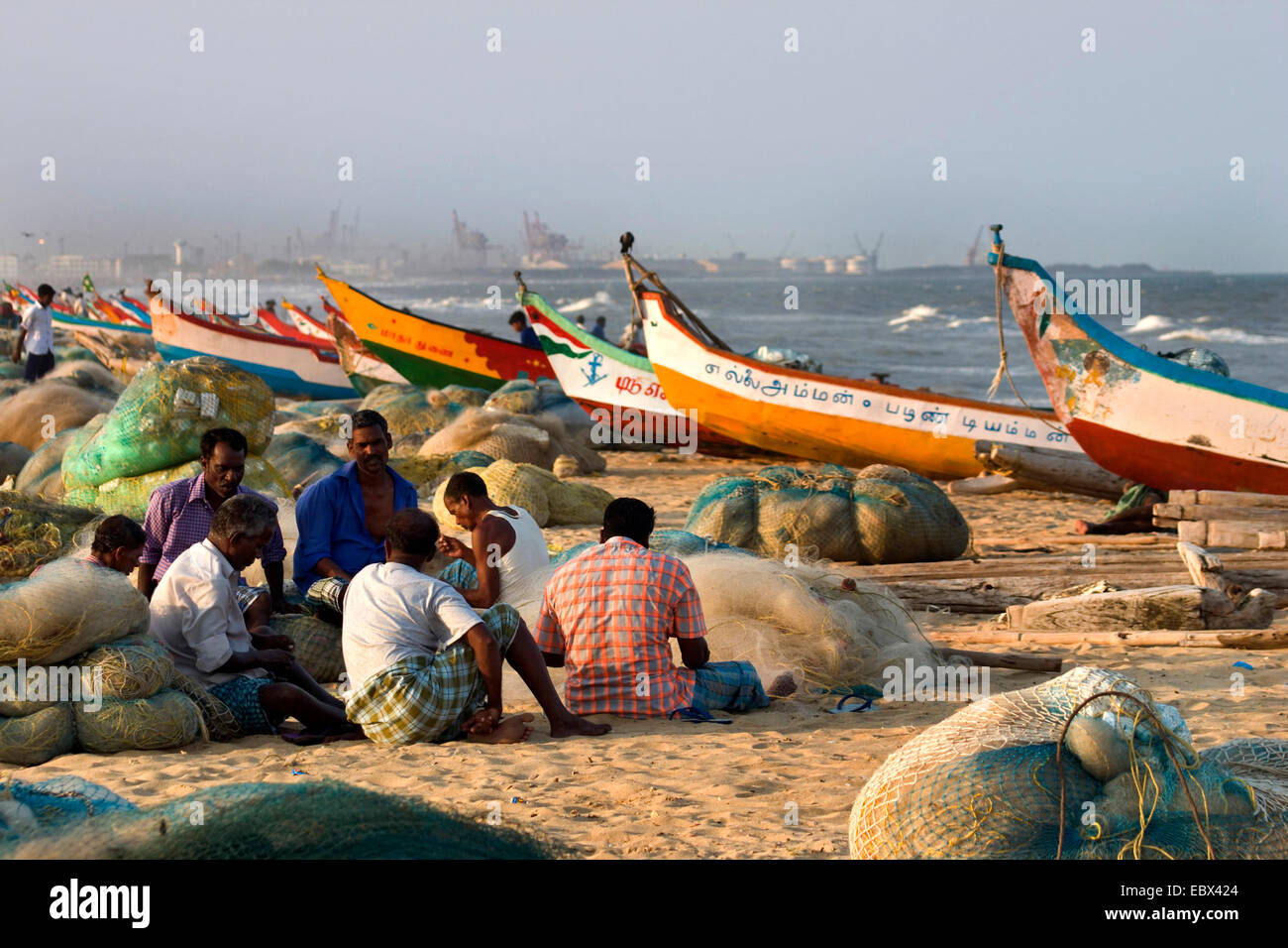 fishermen sitting on sand beach among their boats and nets, India, Tamil Nadu, Marina Beach, Chennai Stock Photo