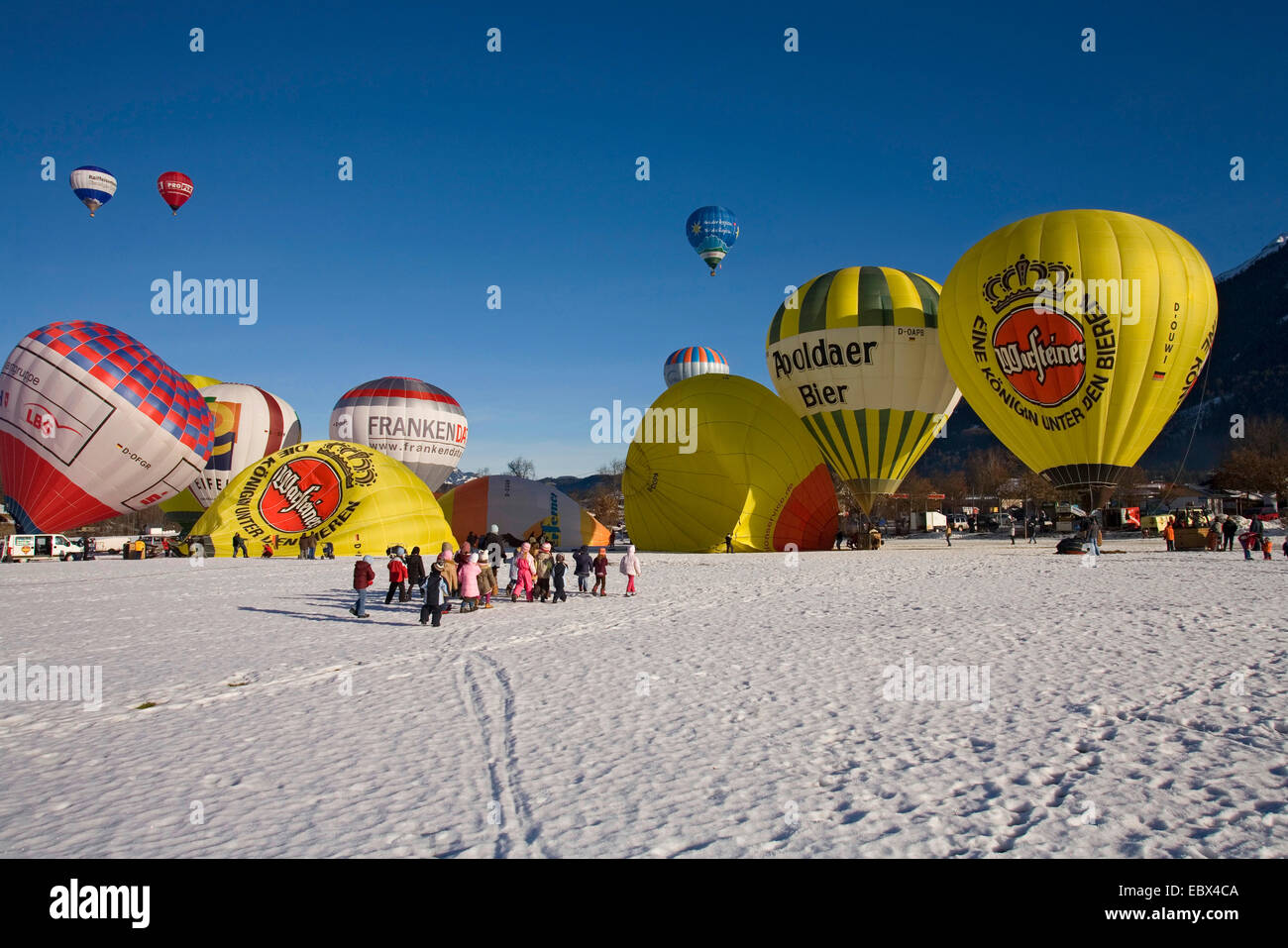 hot-air balloon festival on a snow field with several balloons being prepared for the start or having taken off and a lot of spectators, Germany, Bavaria, Allgaeu, Oberstdorf Stock Photo